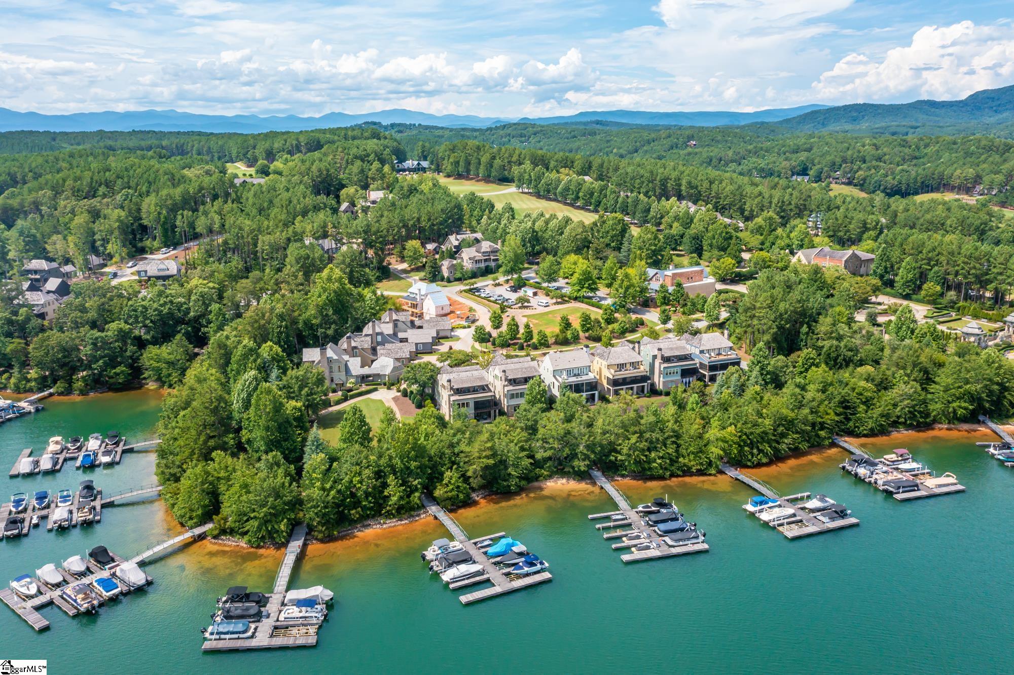 Lake Keowee and the Blue Ridge Mountains offer a serene backdrop for this outstanding home built in 2013 by Pyramid Construction. Featuring five bedrooms and five and a half baths, it was thoughtfully designed by acclaimed architect Lew Oliver and decorated by Fowler Interiors. The exterior is striking but subtle, matching the character of its natural surroundings.     Not that you’d ever grow tired of the view, but 135 Village Point Drive has distinctive outdoor spaces on three different levels—each one large enough for entertaining but comfortable and intimate. The front and lower porch are appointed with bluestone floors, and the ground level has a built-in kitchen ready for your housewarming celebration.   Just steps away from the marina, the lake, and the pools, the location and the view are more than enough to make this property memorable, but the interior is also extraordinary. You’ll enjoy ambient light, ample room, and open space in this expansive home, but you’ll also find peaceful alcoves on each floor. Cozy up to the stone fireplace or have a seat by the prominent kitchen island, which is bound to become a gathering spot as the family chef works. The kitchen has top-rated appliances including a two-door stainless steel refrigerator and a wine refrigerator.   There are den areas and wet bars on two levels. The master bedroom on the main floor opens to the screened in porch and the custom closets are more than big: You’ll have not only storage, but also a system of organization, and the bathrooms will provide the repose of a spa in the comfort of your own home. Other features include a laundry on main level, walk-in storage that includes a second washer/dryer in the basement, and Trex® decking.    The Reserve at Lake Keowee, with its world-class amenities, juxtaposes the feel of a luxury resort and a rustic retreat. Thirty miles of unspoiled shoreline distinguish this 3,900-acre private community, along with a 200-slip marina, a Jack Nicklaus Signature golf course, a tennis center, fitness facilities, Founders Hall, a market, post office, fine dining at the clubhouse, multiple pools, hiking trails, and the welcoming Great Lawn for outdoor events. The quiet, village-like atmosphere represents the essence of intelligent development and community, and the public spaces are meticulously maintained.  Facing south, this elegant and inviting property is the ideal location for family and friends: a retreat, and a home like no other. Schedule an appointment to experience it today, and you could have a remarkable view of this year’s Fourth of July fireworks.