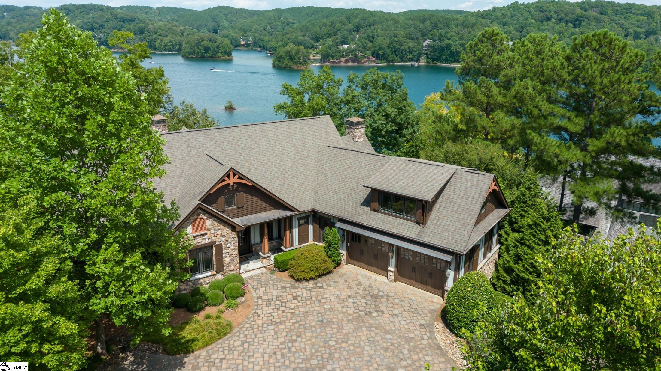 Warm and welcoming custom designed waterfront home with exceptional wide and long views of Lake Keowee and distant mountains.  This 5 bedroom, 5 baths craftsman home has the double benefit of being located close to the clubhouse and community amenities and the rear gate for easy access/egress to nearby towns for shopping and dining. Upon entering the main level, you will immediately be drawn to the wall of windows and the panoramic views overlooking Lake Keowee.  The main level features a private master suite with great lake views and a second guest suite along with an open floor plan kitchen and living area for family entertainment. The kitchen features a large island with accompanying side island for family and guest engagement, Viking appliances with gas cooktop and griddle, double ovens, twin Bosch dishwashers and two walk in pantries (one that can be converted and equipped for future elevator if needed…pad in place).  A large laundry room with significant cabinetry storage leads to steps to a large private guest suite over the garage.  Off the kitchen you will find a screened porch with fireplace perfect for quiet time, reading or just enjoying a warm fire and the views.  Downstairs you will find the recreation room, a wet bar area equipped with ice machine, refrigerator and display cabinetry, an additional private bedroom suite, and a 5th bedroom (great lake view) with shared hallway bath, a second laundry room, a large bonus room that can be used for an office, exercise room, or bunk room and multiple storage areas including a golf cart/lake toys garage with double door exterior access.  Take the golf cart to the waterfront via the beautifully landscaped boulder walls and stone paver path and enjoy expansive views from the fully equipped dock with water, electricity, lift and jet ski ports.  Enjoy a relaxing happy hour with great views of the lake and mountains from the firepit or hot tub on the lower-level patio. The tasteful landscaping and flat access from the road to the large motor court with ample parking makes a pleasing first impression. The home is equipped with many features including a 17kw generator, lightning suppression system, supplemental steam shower system, and radon mitigation system.   The exterior of the home was recently painted, new mulch installed, and the hot tub serviced.  A whole house prelisting inspection was completed, and items addressed including radon mitigation installation.