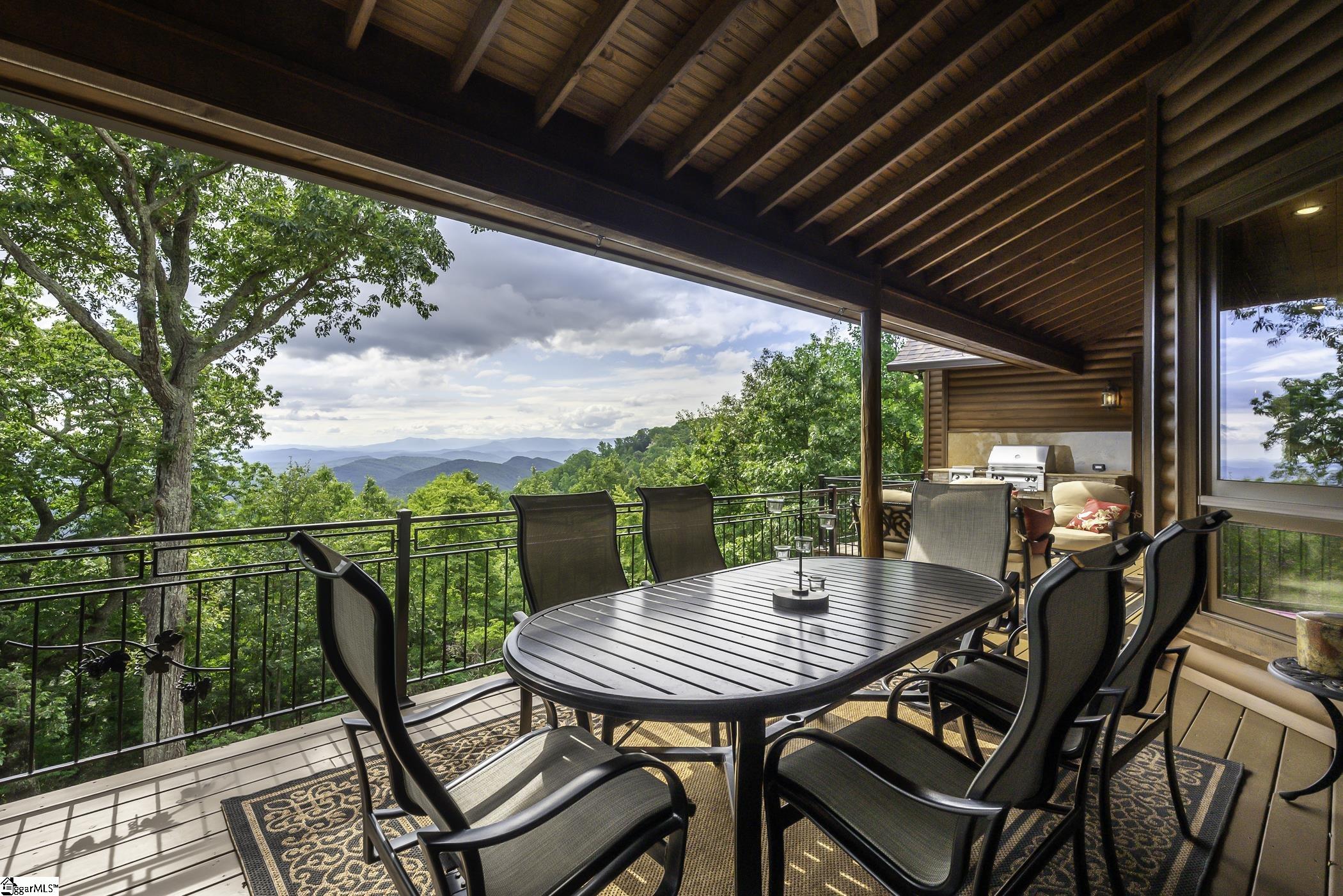 Come see this picturesque Glassy Mountain residence with magnificent wide-range views of the Upstate, Lake Robinson, and Table Rock. Originally built in 1997 by former NFL player and coach Sam Wyche, this four bedroom, three bath home was renovated in 2018 and offers opulent resort lodge living with easy access to downtown Greenville and Asheville. It is perfect for hosting large groups or just relaxing with friends and family.  A dual drive leads to either the garage parking or the convenient main entrance porte cochere.  Through the custom crafted iron entry door, a welcoming foyer opens to the rustic great room, accentuated by a 24 foot vaulted ceiling, a natural stone fireplace, and wood log paneling.  Panoramic windows are everywhere and draw the eye outside to the stunning views.  Curry and Company mercury glass chandeliers create a soft ambiance for the living and dining spaces.   The kitchen is open to the great room and features updated luxury kitchen appliances including:  Liebherr refrigerator and wine chiller: Zephyr beverage center;  Uline ice machine;  American Range stove, double ovens, and warming drawer;  and an Asko dishwasher.  Also included are custom wood cabinets with soft close hardware, under counter lighting and filtered water at the sink.  The outdoor cooking area, with an Alfresco grill and side burner, is located on the deck just steps from the kitchen.  Enjoy the splendid sunsets from the adjacent sitting area flanked by generous windows with remote controlled Hunter Douglas blinds.  The main level primary bedroom is highlighted by a dual bathroom with separate commodes, vanities, and cedar walk-in closets while sharing a double entrance shower with dual showerheads.  The home has two water heaters, one dedicated to the primary bathroom and the other, assisted by a Grundfos circulating pump, serves the rest of the home.  The suite opens to a sitting area on the covered deck with custom iron railing, outdoor shades, and sweeping views. The second bedroom with vaulted two story ceiling and an exquisite bath completes the main level.  Upstairs, a large loft with liberal storage makes for a perfect office and overlooks the main level living areas.  Downstairs is an additional gathering area with a handsome bar containing an Uline ice machine and beverage cooler.  The full bath has been tastefully updated and is shared by the additional two bedrooms.  One bedroom, currently being used as a home office, displays built-in cabinetry with two Zephyr wine chillers.  The other connects to the peaceful screened-in porch with wood burning stove.  There is access to the over-sized garage with sealed floors and My-Q openers that can be operated via keypad and from your smart phone.  There is a great deal of entertaining space on both the upstairs and downstairs decks as well as the new stone patio with electronic ignition gas fire pit and steel surround.  There are two resident-owned propane tanks with one dedicated to the fire pit, as well as two septic tanks.  A new roof has been installed with 50 year shingles.  The landscape has been beautifully updated and features exterior low voltage lighting.  A security system with motion detection has been wired for every entry.  There are speakers in every room as well as outside and the Honeywell thermostats can also be operated from your smart phone.  This approximately 4,000 square foot estate is located on a nearly two acre lot with one of the best views from Glassy.  This IS impressive mountain living.  A full Cliffs golf membership is available.