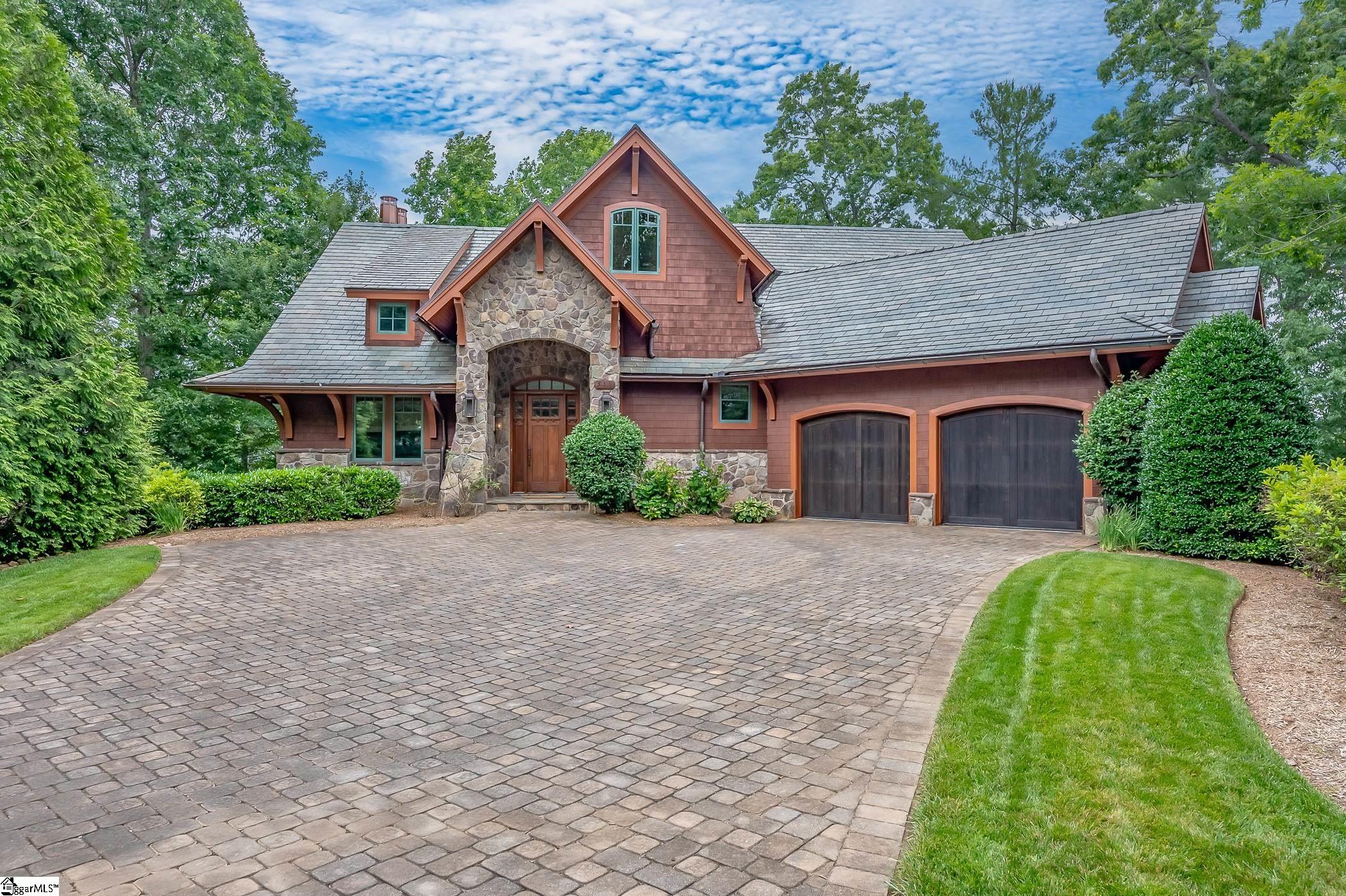 An inviting flat driveway of stone pavers leads to this premier property, located at the end of a cul-de-sac in the highly desirable Cliffs at Keowee Springs community. You are instantly greeted with a harmonious blend of elements, between the wooden arched doors of the two car garage and a storybook-like stone entrance flanked by gas lanterns. Inside the home you'll find an entryway with a soaring two-story ceiling, a wooden platform staircase, and stone tile flooring in different shades of earth tones - leading to the great room. This rich center of the home connects the living area to the formal dining space, screened-in grilling patio, and chef's kitchen with barstools seamlessly. The great room boasts a vaulted beamed ceiling, gas fireplace, custom built bookshelves, ample space for seating and lake and mountain views.Culinarians will delight in the gourmet kitchen. Equipped with a Thermador oven and six gas burner cooktop, Miele dishwasher and Sub-Zero refrigerator/freezer (both appliances camouflaged by custom wood paneling), a built-in Miele steam oven, built-in Miele coffee maker, and a Sharp Insight Pro Microwave drawer, you'll find that style meets function. Every detail has been thought of - from the deep kitchen sink with copper insert, additional cocktail sink in the center prep island, water spicket for filling pots located above the cooktop, soft closing kitchen drawers, and a spacious walk-in pantry. An expansive angled granite high-top counter wraps around the space where family and friends can gather at the opposing bar stools for casual dining and fun. Adjacent to the kitchen is the dining room with doors that lead to the screened porch. A palatial beamed ceiling adorns this stone patio, featuring a 2-story gas fireplace, additional dining area, and built-in grilling station with a copper hood. A slender door from the screened porch provides immediate access to the master suite, located intentionally on this floor for the convenience of 'main level living.' Awake here to long lake and mountain views from the floor to ceiling glass doors that open to a second, separate and private stone balcony. The master bathroom features a deep soaking copper tub, walk-in shower, dual vanities with sinks, and a separate water closet. Also on this floor you'll find a guest suite with its own full bath and a laundry room with custom cabinetry and a porcelain sink. The second upper floor provides an additional guest suite.  The life-style rich lower level includes a wine cellar with tailor made shelving, carpeted movie/media lounge with wall-mounted Jamo speakers, lake room with storage, a full wet bar including a microwave, sink, mini fridge, ice maker, and dishwasher - all complemented by an antiqued copper backsplash. Two additional suites with full bathrooms will wow your guests with calming lake vistas. The terrace level stone patio captivates with main channel views while the covered dock with boat slip is conveniently located to the side of the home, providing tranquil cove privacy. A pebble stone irrigation path winds through the beautifully landscaped grassy regions. An enviably easy walk leads to a covered dock with boat slip, sun deck, and swim ladder. Deep clear water in this private cove, protected from the main channel by a small island, creates a secure spot for swimming. This elegant five bedroom, five bathroom craftsman home also has a Cliff's membership available for separate purchase. Situated a short walking distance to the popular Cliffs Beach Club, you'll find a seasonal lakeside restaurant and bar, pool with fountains and waterslides, stone fire pit, hammocks strung amongst the trees, sandy beach area perfect for swimming, and lake toys available for Cliffs members (at no additional cost to rent) including paddleboards, sunfish sailboats, and more. Enjoy the Cliffs amenities of seven communities for one all-inclusive membership. An exceptional lifestyle awaits you in this luxury lake haven.