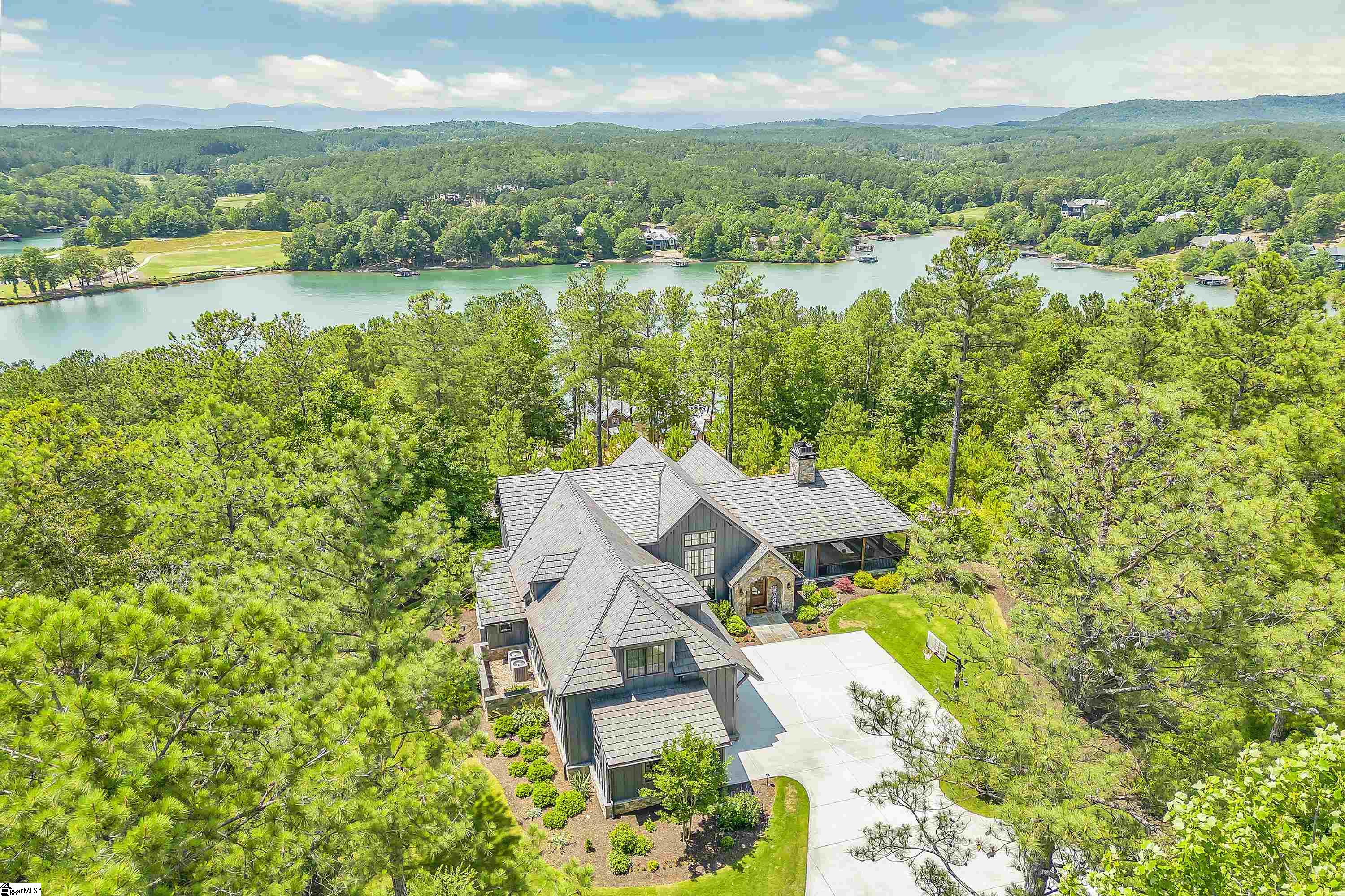 Perched on an elevated site this transitional modern farmhouse truly captivates the beauty of living at The Reserve at Lake Keowee.  A northern facing homesite, the Blue Ridge Mountains and Lake Keowee await in the distance for year-round views and magical sunsets.  This home sits on nearly 2 acres of land with no homes to your left or right and raised from the street below to embrace serenity and privacy.    A winding driveway gravitates you into the grand entry of this spectacular Brad Wright design and Sexton Griffith constructed home built in 2019. The meticulous landscaping with zoysia grass and flower gardens surrounding the house encompass the raw beauty of Lake Keowee living.   Designed for functional living, there is a seamless flow with the open concept floor plan that boast plenty of entertaining space as well as seclusion and solitude.  A plethora of natural light funnels in through the great room windows with water and mountain views in the backdrop.  The wrap around kitchen with a large island allows for ample seating and well-designed kitchen space.  9-inch Oak wood floors reflects the natural light to fill the vaulted wood beamed ceilings.  This home comprises of three true master suites with the Primary Bedroom on the main level and two additional suites on the upper level.  All bathrooms are enlarged with dual vanities and oversized showers. The Primary bedroom connects to the hall from the garage for easy entrance after a long day enjoying all the world class amenities The Reserve has to offer.  Ample storage can be found throughout the home and is tucked away as if you never knew it was there.   The second level boasts a separated family room with a large seating area as well as a murphy bed for additional sleeping arrangements. A bonus room upstairs provides additional seating area and jaw dropping mountain and lake views.   A nearly 400 sq ft. screened in porch with vaulted ceilings can be used year-round with the gas log fireplace television above the mantle.  Step outside to your back patio to enjoy your peace and quiet with a fireplace and private hot tub. This home is must see!  A Premier Membership of $72,000 is required at closing.