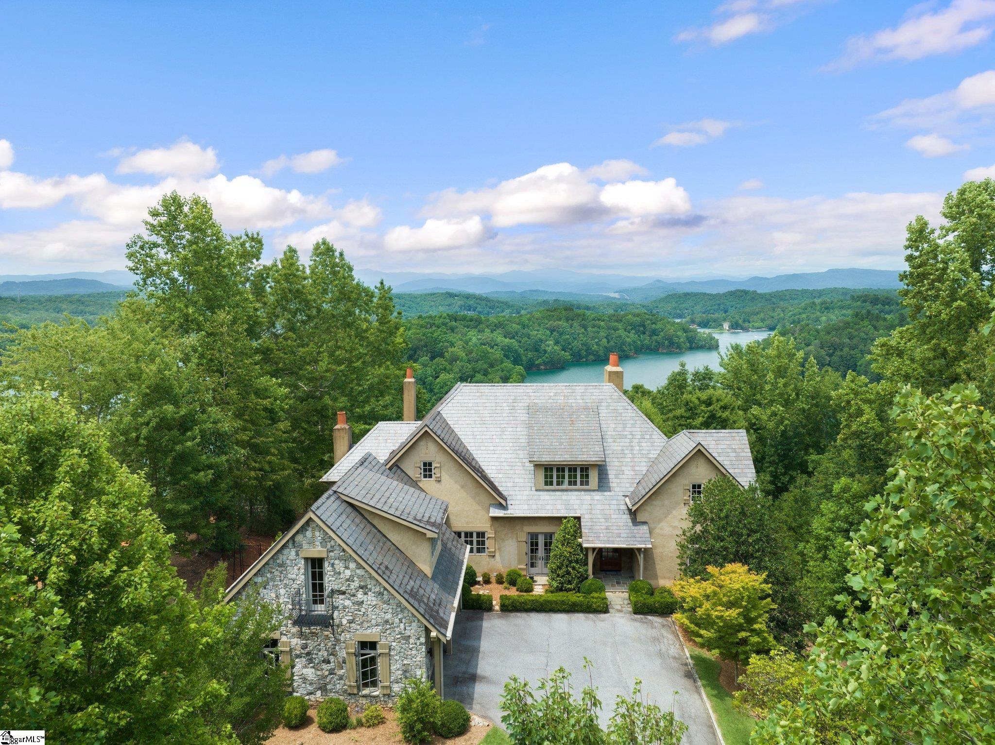 This spectacular French country custom built home is situated on 3.16 acres with views as far as the eye can see. This rare find offers sunrise, sunset, and unobstructed views of Lake Keowee with multi layered Blue Ridge mountains. Enjoy four mountain ranges, Lake Jocassee, lights of Cashiers and Bad Creek Reservoir. 158 feet of lake frontage, distant islands and 180 degree wide open views. Bright, natural light enhances this open floorplan with the help of three sets of glass doors in the gream room. Exposed wood beams, sconces, rustic oak railings, coffered ceilings, heart of pine hardwood flooring, arched built in bookcases, arched doorways, all create the perfect balance for casual and formal entertaining. Perfectly selected antique furnishings highlight the beauty of this home. MAIN LEVEL: Great room, dining room, spacious master with gas log fireplace, gourmet kitchen with huge granite island, customized backsplash, cream cabinets/seeded glass, 6 burner gas stove, Dacor appliances with Sub Zero refrigerator, walk in pantry with built-ins and cozy adjacent keeping room with gas log fireplace. Huge built in china cabinet perfectly situated between the kitchen and sun room. Large laundry room, mud room and gardeners dream with sink and counter with easy access to the outside. The upper level you’ll find a large office with one of the best views in the house, 20x20 bedroom that will become the kids favorite place to go - four twin beds built out of rustic wood, vaulted ceiling with antique whitewood beams and wide plank painted floors with easy access to the large full bath. The TERRACE LEVEL includes rec room with gas log fireplace, three ensuite bedrooms and two large storage rooms. Dock permit has been applied for and path to the lake has been cut in. The $72,000 Premier membership allows access to all the Reserve amenities. The Reserve at Lake Keowee offers a Jack Nicklaus Signature Golf Course, a par 3 practice facility with driving range and outdoor bar, Clubhouse with fine dining, pub area and wine bar, Fitness Center, Hiking Trails, 4 Har-Tru Clay Tennis Courts, Lakeside Resort-Style Pool and Cabana, Settlement Pool, 8 Pickleball Courts, Marina offering both slips and boat rentals, and Market great for lunch and select provisions. This gated community offers many activities including fitness classes, various social clubs, and a high-speed fiber-optic internet system in place. The Reserve at Lake Keowee is a full amenity lakefront golf community with additional amenities planned for the future!