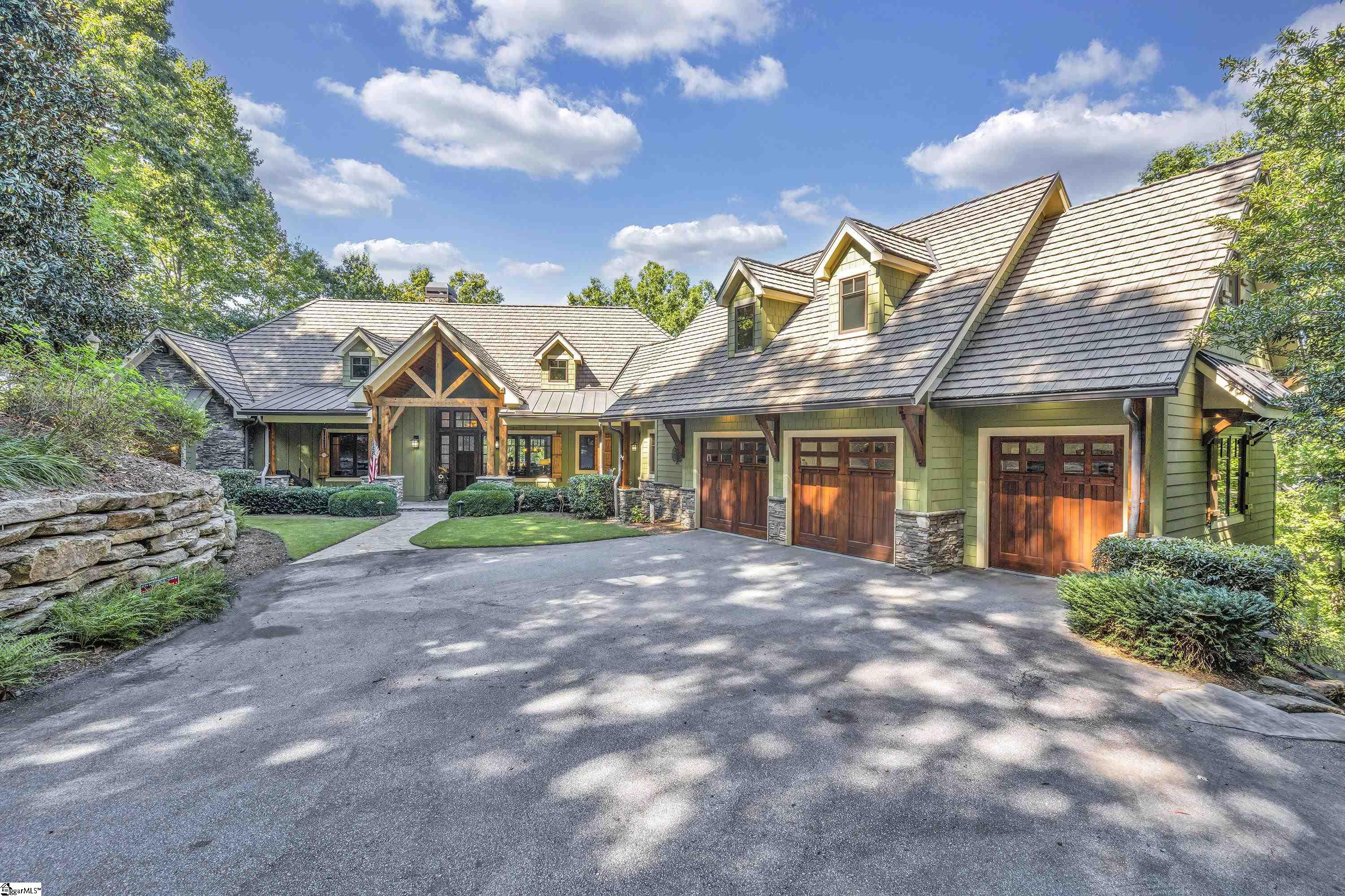This custom lakefront home, with superior craftsmanship from Jeff Holder Builders, is located within the Founders section of the spectacular Reserve at Lake Keowee. Ideally situated in a private cul-de-sac on .85 acres, it offers both seclusion and convenient proximity to hiking trails, conservation lands, and Turkey Ridge Park. Spacious rooms and extensive outdoor decking and porches have been brilliantly designed to maximize your view of the distant mountains, a protected island to the west, and of course, the sparkling open water. The home boats 5,460 finished square feet, along with another 931 sf of partially finished space—and 2,471 sf of porch and deck space! The exterior features a thoughtful blend of natural stacked stone, board and batten, maintenance free-hardie board siding and solid rough sawn beams. Also a fire resistant tile roof. The nine-foot solid wood entry door with sidelights and transom sets the tone of a welcoming mountain retreat as you step into a vaulted great room and an expansive open floor plan. Hickory flooring throughout the main level contrasts beautifully with massive columns that make the space distinctive. The great room features a wood-burning fireplace, a built-in entertainment center, striking woodwork, ample cabinetry, and expertly crafted windows to display the view beyond them. The chef’s kitchen is complete with oversized custom knotty Alder cabinets, Wolf double ovens, a Sub-Zero refrigerator, and a GE Profile Induction range. The amount of rich looking wood gives the room a hint of a midcentury feel, but this noteworthy kitchen is both inviting and a practical workspace for the serious chef or entertainer. Close by is a dream pantry—massive in size, with a variety of built-in solid Alder shelving, plus a full-size freezer. Just off the kitchen is a vaulted screened porch with a stacked stone fireplace and a grilling area perfect for fall football games. The large dining area is well positioned between the great room and the kitchen with access to both the sun deck and porch. The master suite on the main level has its own private “sleeping porch,” plus a separate reading or yoga room, and there is an office/second bedroom on the main level with a full bath, convenient to the master. The home has a generously sized three-car garage, and the huge bonus room above it would be perfect for an exercise room or another bedroom. The home has two private ensuites on the lower level. The family room there has a coffered ceiling, a fireplace, a wet bar, and appliances, making it already suited for your first guests. The large lower-level deck is prewired for a hot tub and/or outdoor shower. It leads to a landscaped path with boulder steps and onto a Reserve standard custom dock with a boat lift and EZ-step ladder. The shoreline features 233 feet of rip-rapped frontage. Other features include a whole house generator, solid IPE wood decking and porches, concrete shingle roof tiles, a central vacuum system, and a security system. The Reserve at Lake Keowee is a master-planned community that features over $100 million in amenities including a Jack Nicklaus Signature Golf Course, a lakeside resort-style pool and cabanas, and a marina offering both slips and boat rentals. Premier membership ($72,000) is required with purchase.