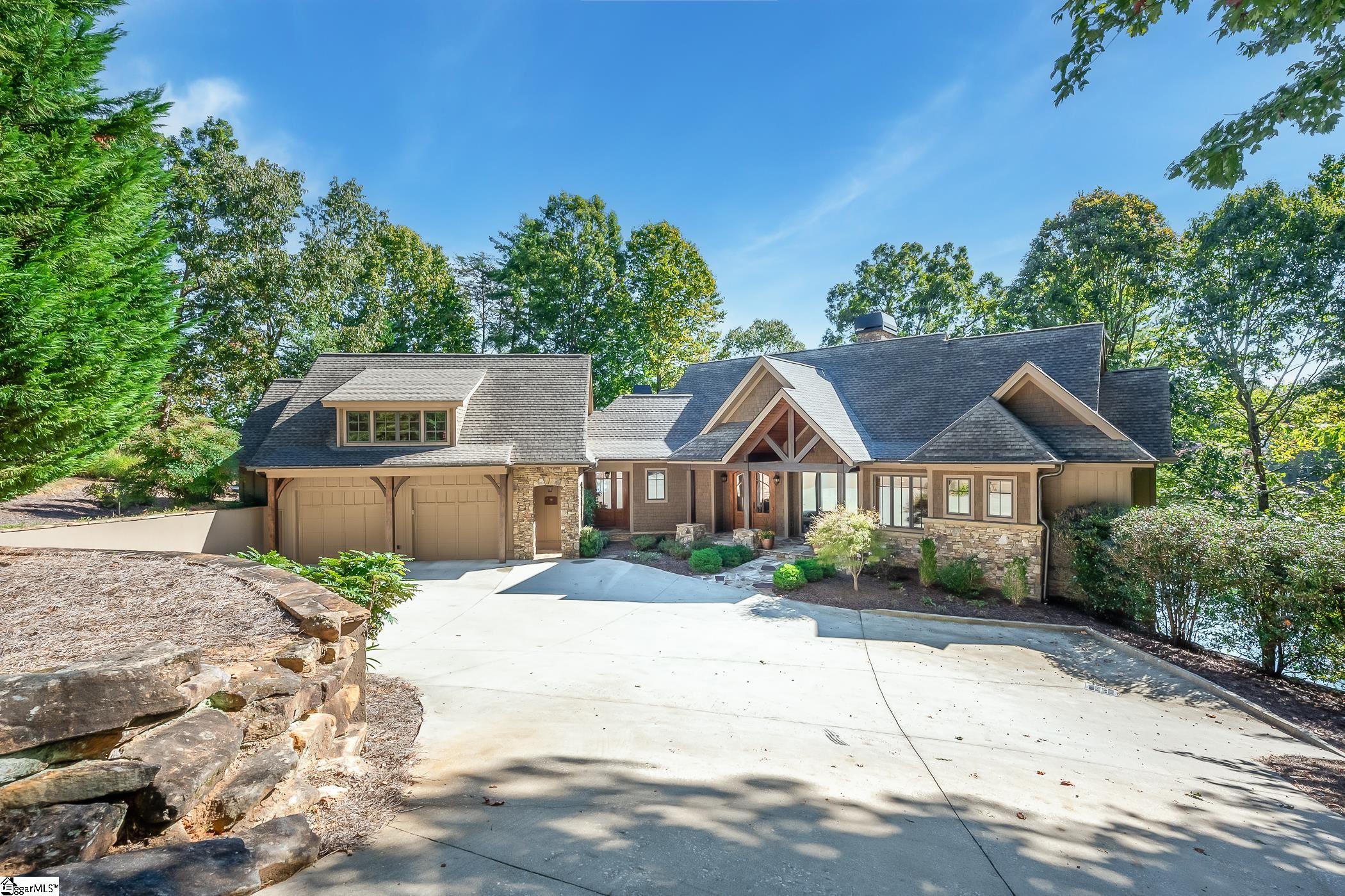 This exceptional lake-front home, located in The Cliffs at Keowee Falls community, exudes quality craftsmanship and attention to detail. As you arrive, a gracefully curved driveway leads to the inviting wooden and stone exterior. The double doors, featuring elegant windows, open to reveal an impressive entryway, providing a seamless transition into the vaulted great room. Its hardwood flooring beautifully mirrors the tongue & grooved ceiling, showcasing a striking two-story stone fireplace as the centerpiece.  Flowing effortlessly from the great room is an open concept kitchen and dining room, designed to delight any culinary enthusiast. This kitchen boasts an expansive amount of countertop space for food preparation, walk-in pantry, KitchenAid double wall ovens, a gas cooktop, a KitchenAid refrigerator and freezer with an ice maker, two sinks, an island, and a dining bar, all complemented by stunning rustic cabinetry. Adjacent to the kitchen and dining room, a thoughtfully placed screened porch awaits, adorned with another stone fireplace and a wooden vaulted ceiling. This sanctuary-like space offers sweeping views of the lake and is further enhanced by two smaller open-air decks, with one specifically tailored for grilling.  Also on the main level, you'll discover a laundry room, complete with a desk nook, custom cabinetry, and a sink. Additionally, the main level boasts a powder room, a wine cooler nook, a cozy formal office, and the master suite, ensuring every need is accounted for.  The master suite features plush carpeting, a vaulted nickel gap board ceiling, and captivating lake views. Imagine waking up each morning to the serene waters of Lake Keowee! This splendid suite also offers a thoughtfully designed spa-like bathroom, complete with a generously sized tiled walk-in shower, strategically high-placed windows for natural light, dual sinks, a spacious walk-in closet, a separate water closet, and a luxurious soaking tub.  The terrace level of this home presents even more expansive views of the emerald lake waters. A carpeted second living room, accompanied by a wet bar and a stone fireplace, sets the perfect ambiance for relaxation and entertainment on this lower level. Additionally, three generously sized guest suites await on this floor.  An additional laundry room on this level adds a touch of convenience. For outdoor enjoyment, a covered but open-air sitting patio mirrors the upper screened porch, offering a serene sanctuary to unwind after a day of lake activities.  Follow the gently sloped terrain, adorned with mature bushes, to your private covered dock, where endless opportunities for boating and swimming await. Furthermore, this well crafted home features a two car garage with a full bonus suite with bath, providing ample space for versatility and customization.  Experience the benefits of a club membership with The Cliffs, an elite community that boasts seven exclusive clubs throughout the area, all included in a single membership (available for separate purchase). Take advantage of a variety of world-class amenities, such as state-of-the-art wellness centers, world-renowned golf courses, inviting pools, formal dining restaurants, and delightful lakeside al fresco dining options.  Don't miss your chance to experience the relaxing lake lifestyle with this exceptional property!