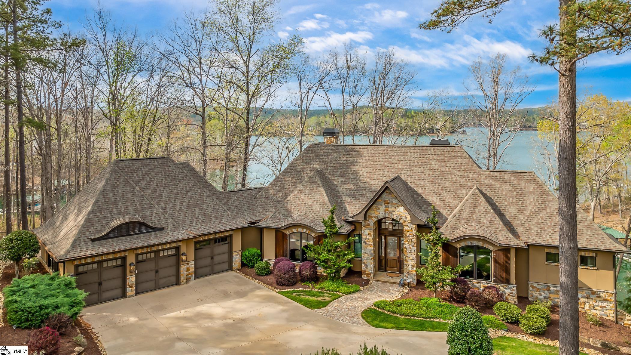 The wait for your dream lake home is finally over! 104 Mountain Shore Trail will be sure to check all your boxes. This 4,192+/- sq ft, four bedroom, three and a half bath craftsman style home is situated perfectly on one of the best waterfront properties on Lake Keowee. With over 180 ft of shoreline and located in an area shielded by boat wakes, you’ll be able to swim, float, kayak, or paddleboard all season long! Whether you prefer to cozy up by the waterfront fire pit or watch the game from your indoor/outdoor bar, this custom home offers areas for relaxing or entertaining inside and out.  This well-designed home built by Dillard Jones in 2017 maximizes the spectacular lake and long-range mountain views. As you enter the foyer, you’re immediately drawn to the view through the vaulted ceiling, arched transom window, and stacking sliding doors in the Great Room. A gas fireplace is smartly situated in the corner with stone from floor to ceiling. The built-in cabinetry creates additional storage space and home for your TV.   The bright and open kitchen is well-appointed with a Wolf four-burner cooktop, pot filler, Sub-Zero french-door refrigerator, Bosch microwave and double-ovens. The combination of the granite countertops, stone backsplash, and nickel-gap detailing creates the ideal environment for the chef in your family.   Off the kitchen, you’ll find a cozy casual dining area with sprawling views and access to the covered, screened porch. The porch can be used during any season due to the gas fireplace. Another spacious porch is located off the Great Room with a built-in gas grill. This uncovered area allows for natural light to flow inside and for you to enjoy the sunshine year-round.  If you desire more room for hosting then walk through the wine bar situated with a beverage cooler, cabinetry, additional counter space and into the formal dining area. You’ll be able to accommodate all your friends and family.  Located off the 3-car garage is a large utility room and arrival center. You’ll never yearn for more storage with the ample cabinetry and coat closet. This area boasts a utility sink, desk, bench with hooks, room for a washer and dryer, and a powder bath right around the corner.   On the opposite side of the main-level, there is a spacious office with hardwood floors overlooking the beautifully landscaped front yard.  Across the hall, the Owner’s Suite is the ideal sanctuary. Enjoy the view of Lake Keowee and Blue Ridge Mountains from a comfortable seating area near the bay windows or sip your morning coffee from the porch off the suite.   You’ll pass his & her closets as you walk to the Owner’s Bathroom from the bedroom. Here you’ll find two vanities with an area designed for applying makeup along with a soaking tub and walk-in shower.   Descend the staircase or utilize the elevator to access the lower-level walkout. The lower-level features a recreation room with a gas fireplace, billiards room, an indoor/outdoor wet bar, wine storage, three more bedrooms, two full bathrooms, and an exercise room. The wet bar includes a sink, dishwasher, beverage cooler, and mini refrigerator so you can entertain with ease. A climate controlled wine cellar has plenty of room to store your favorite bottles. The tiled floors allow you to come in from the lake worry-free while the carpeted bedrooms create a cozy environment.  The path from the lower-level porch leads you to the dock. For your convenience, you can walk to ride your golf cart or GEM car to the dock or any of the close amenities.   A Cliffs membership is available for separate purchase, allowing you to indulge in the recreational offerings available at all seven clubs located throughout South and North Carolina. From award-winning golf courses to formal dining restaurants, wellness centers with tennis and pickleball courts, and more.