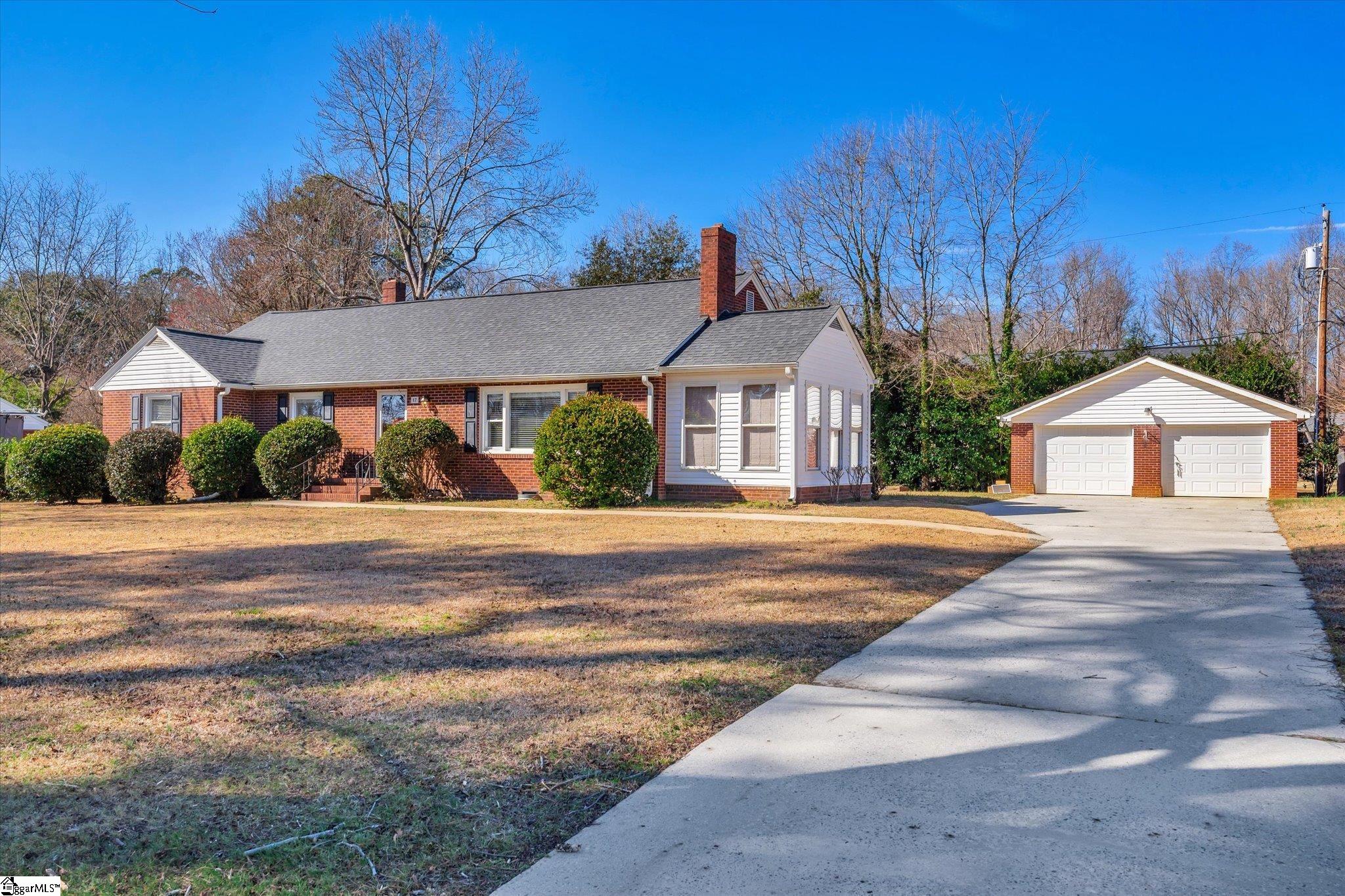 As you enter this 4 bedroom 2 bath brick home from the front paved walk into its spacious living room you will notice its beautiful hardwood floors and brick fireplace. Right off of this room is a sun room with lots of windows and a dining room with hardwood as well. Step through the doorway to the spacious kitchen with its painted cabinets. Large walk in laundry room just off of the kitchen. Hardwood throughout most of the home and windows have been updated to vinyl. Exterior has concrete drive and 2 car detached garage with extra storage around back! Located in the heart of Williamston conveniently to local shops, restaurants and The Mineral Spring Park! The fourth bedroom could be used as an office or a bedroom with plenty of closet space and built in book cases.