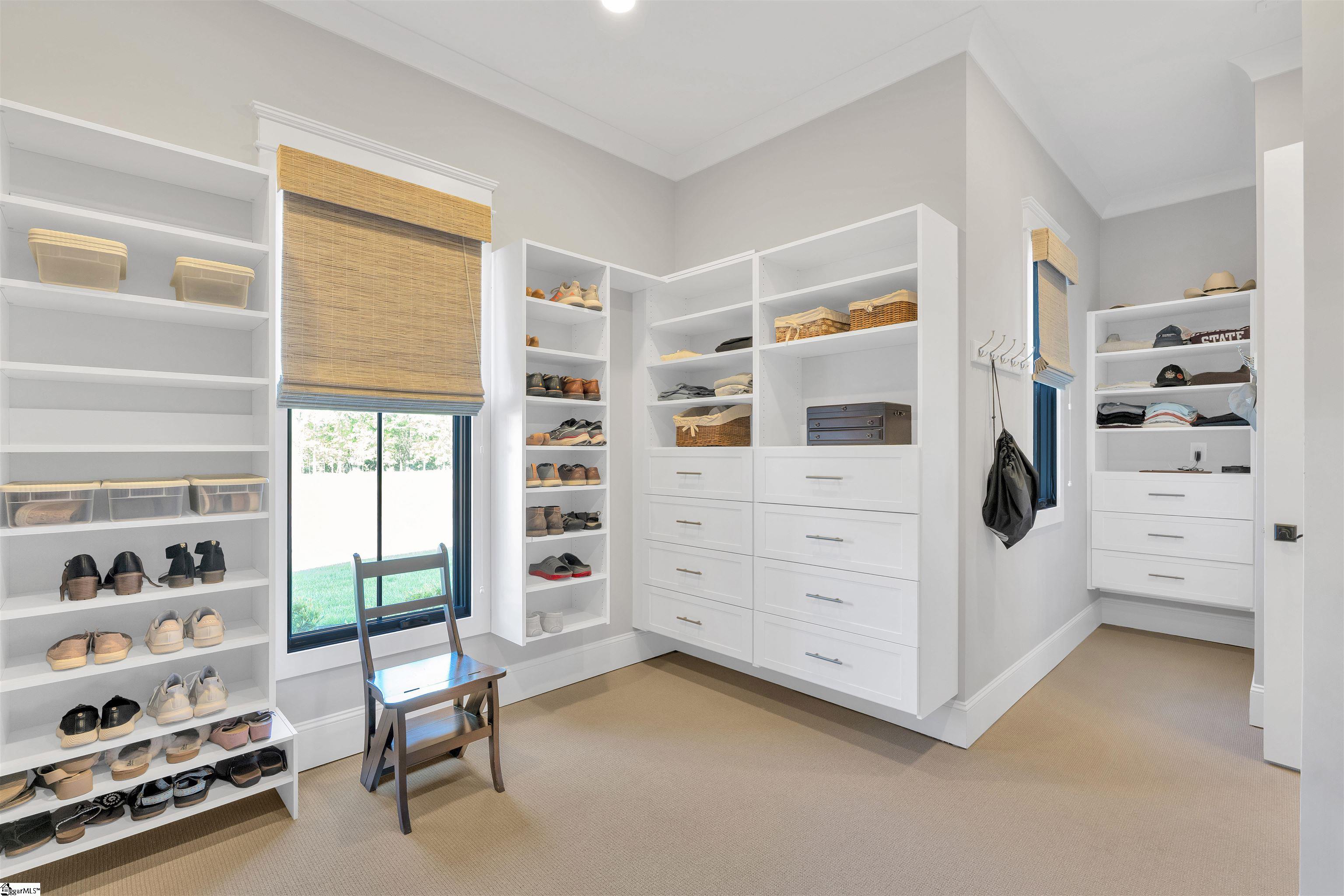 Luxurious primary closet with custom built-ins and a charging station for devices.