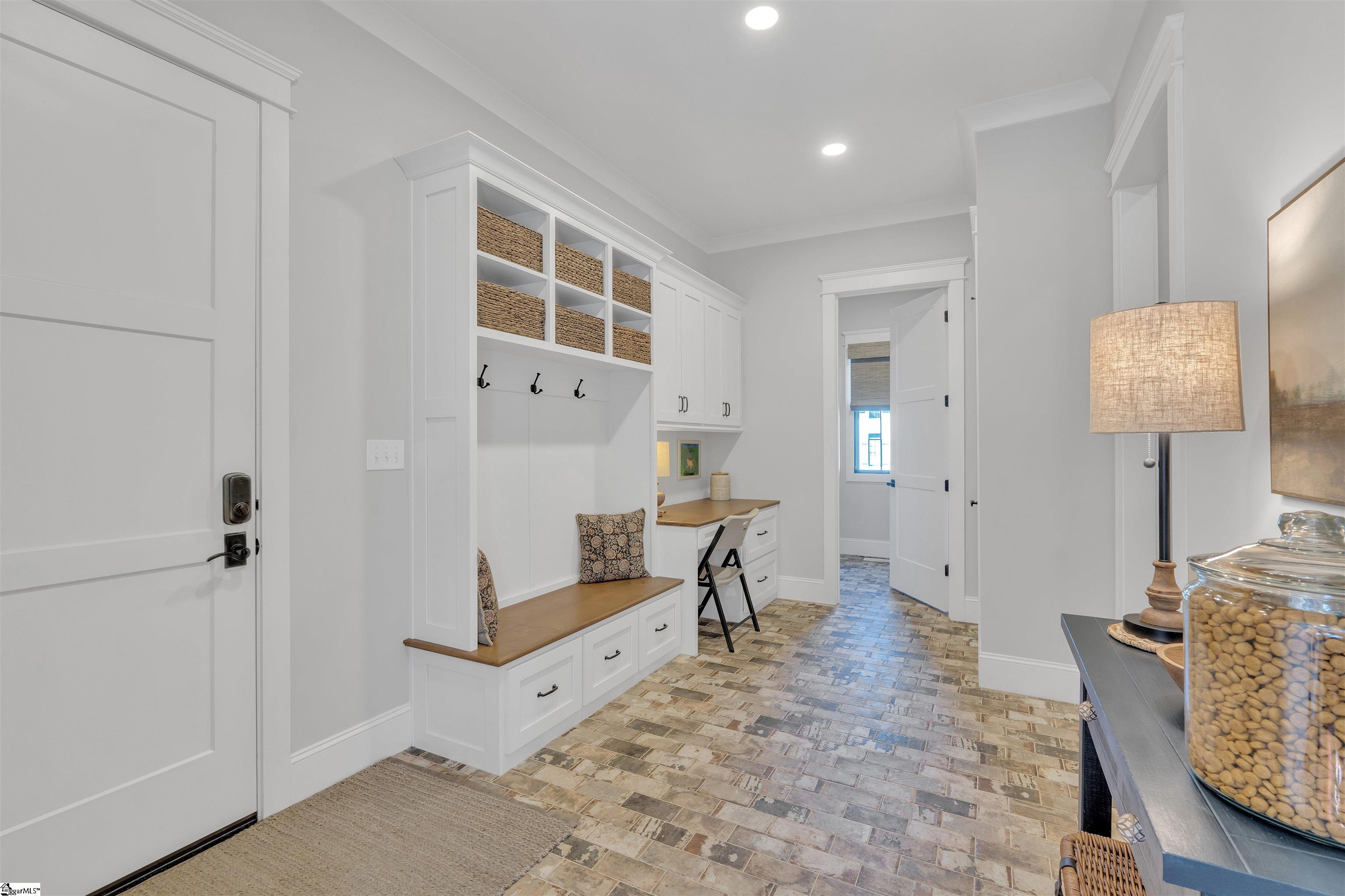 Great sized mudroom just off of the kitchen with a custom bench and desk and leading to the office.