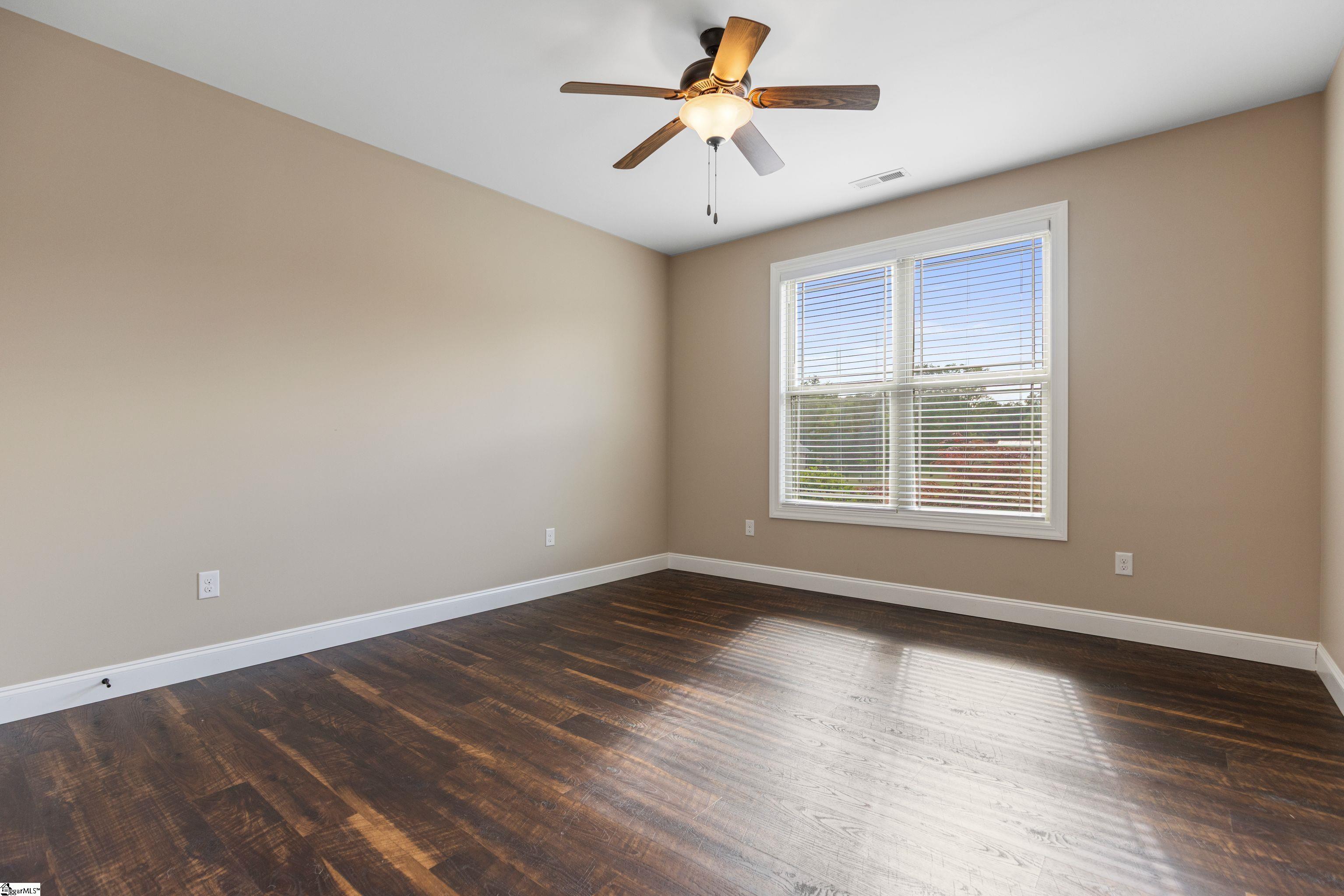 Cozy third bedroom with ceiling fan and neutral décor ideal for guests or children.