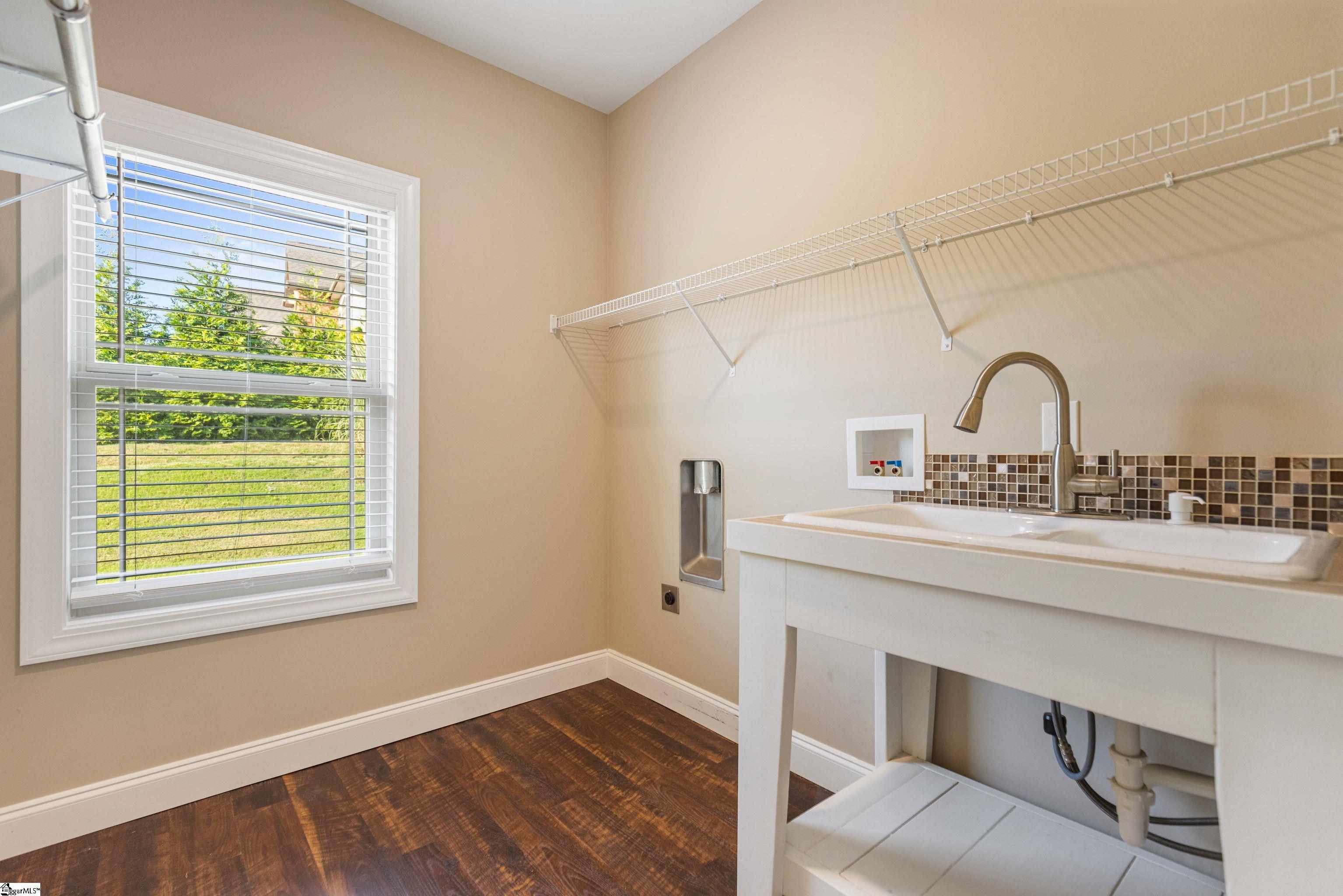 Spacious laundry room featuring a utility sink, ample space to hang clothes, and a large window that fills the room with natural light.