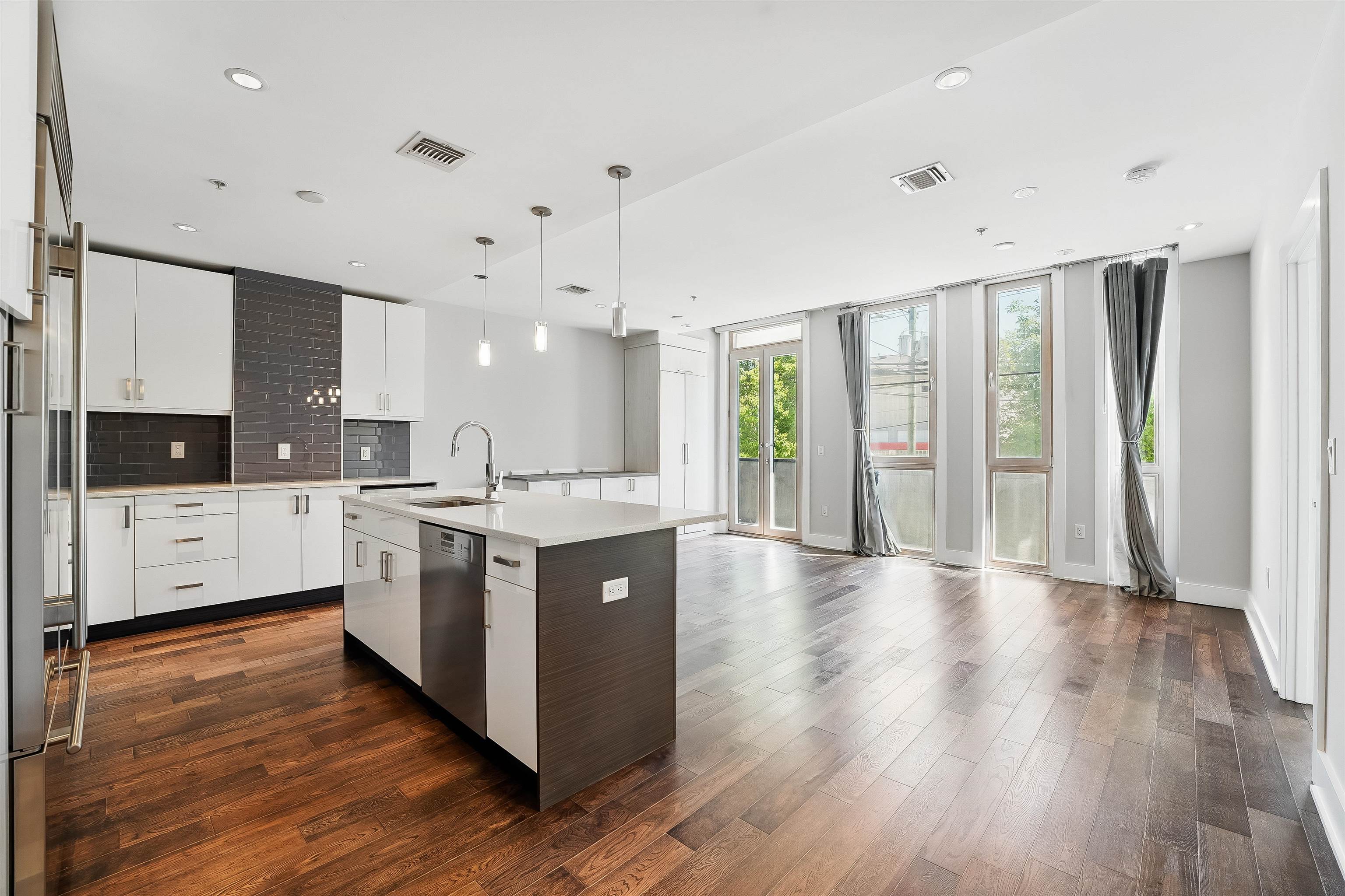 Experience upscale urban living in this stunning 780 SQFT east-facing one-bedroom at Tribeca West. Designed for comfort and style, this spacious home features a sunlit living and dining area with floor-to-ceiling windows and private balcony access. The chef's kitchen is outfitted with premium Wolf, Sub-Zero, and Miele appliances, Caesarstone countertops, Aya custom cabinetry, wine cooler, and a breakfast bar that seats four. The bright primary bedroom offers generous space, designer closet, and serene eastern exposure. A spa-inspired bathroom includes Graphite Porcelain tile, floating vanity, Kohler fixtures, and a soaking tub. Additional highlights: wide-plank hardwood floors, Central A/C, Budd Central Vacuum, recessed lighting, Intus energy-efficient windows, automated blinds, in-unit washer/dryer, and Smart Home features. Tribeca West is a LEED-certified, professionally managed elevator building built in 2014 with steel and concrete construction. Ideally located in the heart of Hoboken near NYC transit, parks, shops, and dining. Very Low Monthly Maintenance Fees! Rentable garage parking available nearby.