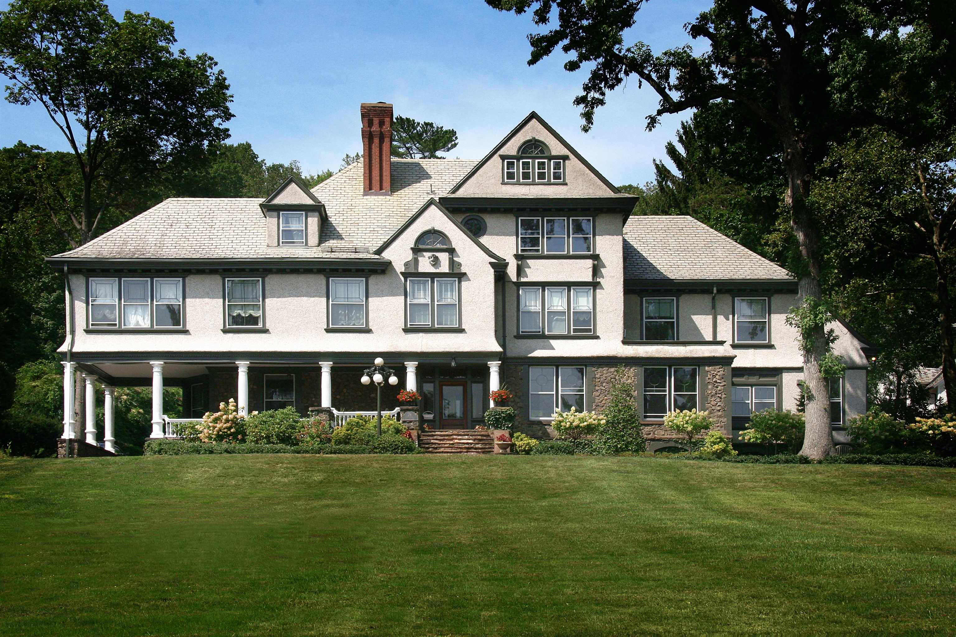 NEWPORT MEETS MONTCLAIR A LANDMARK ESTATE OF RARE DISTINCTION! bA rare opportunity awaits to own one of Montclair's most distinguished estates an iconic residence celebrated in Estate Homes of Montclair for its architectural significance, timeless elegance, and remarkable scale. Inspired by the coastal grandeur of Newport's Gilded Age and infused with the refined charm of Montclair's Estate Section, this historic 8, 400 SQFT masterpiece sits on 1.40 acres of manicured grounds, offering extraordinary privacy just minutes from Manhattan. The home boasts 8 bedrooms, 8.5 baths each set within beautifully detailed living spaces. Classic architectural elements stately columns, paneled walls, beveled glass windows, ornate millwork, and soaring ceilings showcase unmatched craftsmanship, while expansive rooms such as the formal dining room, sun-drenched library, wraparound family room, and home theater bring a modern sense of livability and comfort. Rooms from the third level offer unobstructed views of the New York City Skyline. Enhancing the property's appeal, a separate rentable carriage house at the rear provides 2 bedrooms and 1 bath ideal as an in-law suite, guest residence, or for generating sufficient rental income to offset the majority of the property taxes. Outdoors, two covered porches, a bluestone patio, fresh landscaping in a generously sized property create an inviting backdrop for everything from quiet al fresco dinners to lively gatherings.