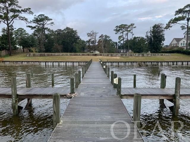 This is arguably the most beautiful homesite in all of Dare County.  A double lot containing 1.36 total acres offers the opportunity to construct an estate style homeplace.  The sheltered deep water harbor of Jean Guite Creek offers safe boat docking, along with skiing, fishing, and swimming.  There is a 6' wide by 125' long Epay PIER which includes 2 large boat lifts, mooring pilings, two 25' finger piers, water service, and electric service.  This Pier is marina quality.  The heavy duty, double reinforced vinyl bulkhead has been constructed with the best craftmanship and materials available.  The ground elevation is estimated to be 10', and the property is cleared, and maintained in a park type setting. This is a one of a kind property!