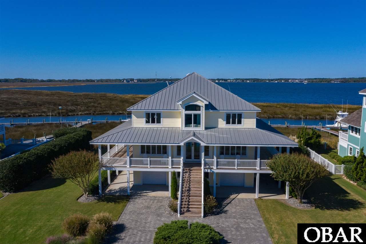 Welcome home to this custom built, sound front, premier estate home with two levels of porches and decks offering panoramic sunset views of Shallowbag Bay and sunrise views of the Albemarle Sound. Sited on a lot and a half, located in the gated, amenity rich, world-class marina community of Pirates Cove. This home offers over 4,000 square feet of livable luxury.  No construction expense was spared and many low-maintenance, commercial construction methods were utilized in the unparalleled construction of this residence including. The thoughtful design and sophisticated architectural elements include a welcoming elevation, an open floor plan with hardwood floors in all living areas and bedrooms, Italian marble floors, upgraded fixtures and solid surface counters in bathrooms, clear pane windows for optimal views, gourmet kitchen with stainless appliances and granite counter tops, deluxe trim and millwork and solid doors throughout. The home boasts five bedrooms including a main level en-suite bedroom, five full and two half baths.   Lower level has a half bath, tackle storage, billiards room, workshop and 2 extra-deep garage stalls. There are two boat slips directly behind the home for a total of 70 feet of deep water dockage. The space could be used for two boats, or a boat and jet ski dock. Community amenities include: security, two pools, volleyball court, tennis courts with pickleball lines, fitness center, a community center, miles of docks, a marina, tiki bar and seafood restaurant.