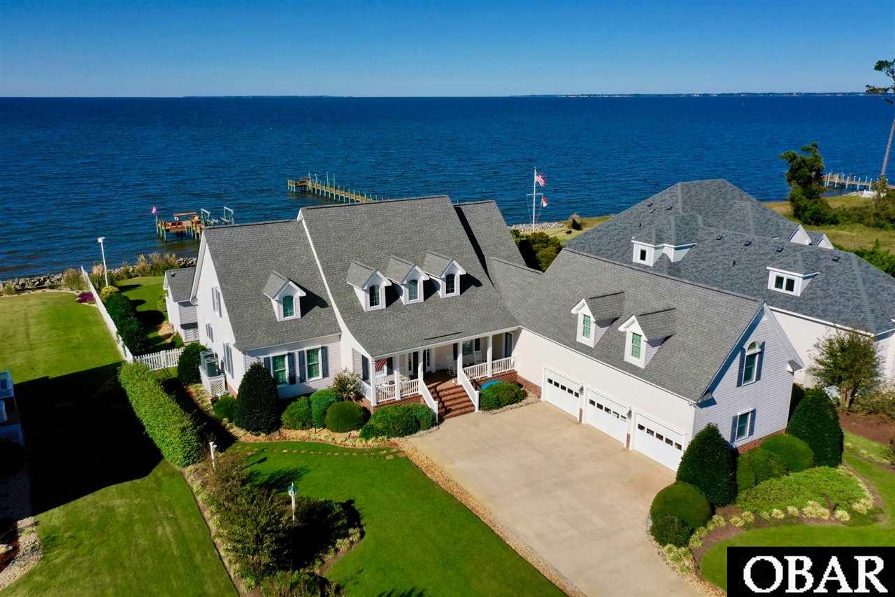 What waterfront dreams are made of! This Coastal Masterpiece will take your breath away and win your heart. Where the backdrop of nature commands center stage and wows the moment you cross the threshold. Majestically sited on the Albemarle Sound offering the most stunning sunsets, this lavishly landscaped 25,000 sq.ft. homesite welcomes you HOME with open arms. This soundfront beauty sits in a X flood zone where NO flood insurance is required. Located in the prestigious community of Heritage Point on Roanoke Island where the town of Manteo carries a strong sense of heritage and lends an idealistic lifestyle with focus on family and community unity. Adorned by an abundance of custom finishes with sophisticated simplicity, and designed to replicate the Crabapple Cottage by William E. Pool. This 4 bedroom (all are en-suites with sound views), 7 bath (6 full and 1 1/2 bath) estate comes complete with a private pool, pool house, an apartment over the 3 car attached garage, hurricane shutters, irrigation system, pier and boat lift. The main level features a welcoming covered front porch with 2 story entrance foyer, a great room boasting a gas fireplace, tray ceiling, oversized windows and transoms, crown molding, hardwood floors, custom built-ins, and of course water views, the renovated chef's kitchen has silestone and granite countertops, tile backsplash, stainless steel appliances, soft-close custom cabinets, a 2-level buffet bar, wet bar, wine fridge, and informal cozy dining area with plantation shutters and gas fireplace making this the perfect space for entertaining family gatherings. Just off the breakfast nook is an 11.5 x 24 ft 3-season room where you can relax with your morning coffee while watching the sunrise, or unwind in the evenings gazing at magnificent sunsets. Conveniently located off the kitchen is the formal dining room displaying a wedding cake tray ceiling and chair railing, a powder bath, well utility room, and dry entry from the oversized 3 bay garage with 10x7 ft high doors. Over the garage is an apartment/recreation room with kitchenette. The glorious master bedroom is also on the main level and features 6 ft high windows, tray ceiling, a spacious master bath with home office, built-in cabinets, and his and her walk-in closet. Seller is installing a brand new custom tile shower to be completed by end of January. Upstairs will not disappoint. There are 3 more master suites complete with private baths and sound views, plus multiple-walk-in storage rooms. The exterior features low-maintenance vinyl siding and fencing, hurricane shutters, a lavishly landscaped yard with an irrigation system, HVAC with 4 zones, a 22 kW generator hooked up to run refrig/freezer/HVAC & electrical systems, a well that services the pool and irrigation system, an inviting pool and pool house with finished upscale full bath and storage. You will also enjoy the pier boasting a boat lift, built-in seating, and fish cleaning table. The family will love crabbing, fishing, boating, and paddling on the expansive waterfront playground. Please read the "house notes" in associated docs for a complete list of features there's just too many to name. This soundfront compound is a must see and ready for a new family to make wonderful memories.