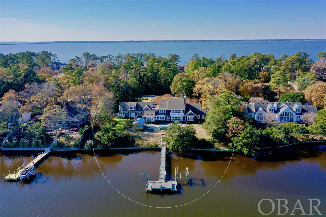 This remarkable waterfront home in the exclusive gated community of Martin's Point will beckon you home with sprawling water views, salt water pool, appointed details, grand spacious rooms and private 1.29 acre homesite (2 lots) with 200 feet of water frontage. The main home has 3 master suites with 5200 sq. ft  and the apartment includes 1 bedroom and 1 bath with 611 sq. ft. Quality constructed by Shoreline Builders and a design that boasts a timeless style with a truly lovely floor plan. You'll immediately melt into the home's commanding presence when entering the column flanked circular driveway beautifully crowned with this 4 bedroom, 6 bath (4 full and 2 half) waterfront estate. Located on a high bluff and nestled on one of the most coveted areas of the neighborhood, Ginguite Creek. The owners chose this location over sound front because it provides extra protection from harsh weather, high water, and nor'easters. Remarkably built through and through using high-end materials above industry construction measures. The main house boasts 5199 sq. ft, 3 master suites, a two story entryway where you will immediately be captivated by breathtaking water vistas, and fine craftmanship. The first level features the great room with an east wall of windows capturing sparkling water views of Ginguite Creek, cherry hardwood floors, custom built-in cabinetry, gas fireplace, tray ceiling, a stately dining room, a cozy library/office wrapped in mahogany with a stone fireplace and gas logs. The carefully designed kitchen is wonderfully functional with granite countertops, stainless steel appliances, a countertop range, a double wall oven, and huge walk-in pantry. Adjacent to the kitchen is a breakfast nook and sun room with high ceilings and skylights offering an abundance amount of natural light. A dry entry into the home from the 2 car garage and breezeway offers convenient access to the kitchen to quickly unload provisions, a powder bath, and a utility room. The main master bedroom is located on the opposite wing for extra privacy enjoying high ceilings, walk in closet, and a grand bathroom with his and hers vanity, tile shower and soaking tub. Upstairs the media room/den takes center stage with more custom built-in cabinetry, huge full bar with prep sink, and sensational water views. Also on this level is another waterfront master bedroom with ensuite bath, an additional master suite with private bath, and a billiards room. An exterior staircase over the garage features a one bedroom apartment with kitchenette perfect for extended family, guests or rental space. Outside does not disappoint with a large saltwater pool, a pier with boat lift, an outdoor Kitchen with wood burning fireplace excellent for roasting oysters, a TV cabinet, and a half bath! Enjoy all of the amenities, security & privacy offered in this sought-after community complete with guarded gate 24/7, Marina and Boat Dock, stocked ponds for fishing, playgrounds, waterfront pavilion for hosting gatherings, and boat & trailer storage.
