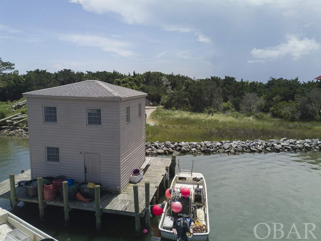The "Fish House", built by Ocracoke legend Sam Jones is one of a scant handful of structures that sit atop Silver Lake Harbor.  The 2 story frame structure consists of unfinished open space.  The 160 feet of shoreline has recently been protected with rip rap and natural marsh grasses.  Over 13,000 feet of highlands on road side of property should accommodate septic system, 2 bedroom septic permit pending.  This is a unique opportunity to have a one of a kind cottage, perched atop Silver Lake Harbor with in place deep water dockage at your doorstep.  Current use of property is as it's name suggests; serving as local fisherman's base camp.  Showing by appointment only