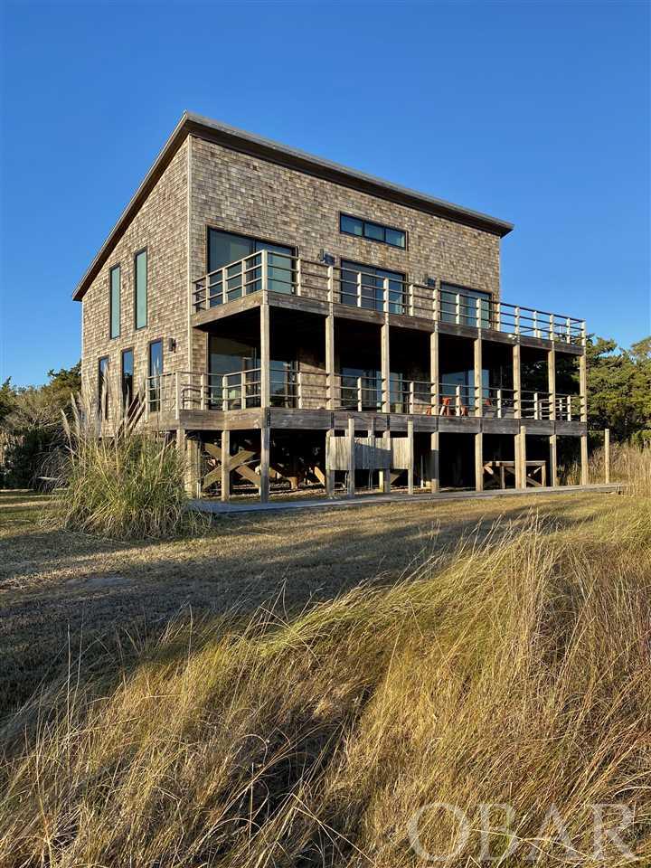 This is a truly spectacular property built on over an acre at the end of a dead end road overlooking expansive salt marsh onto National Park lands.  Included is a 7,885 square foot lot which conveys with it's own 2 bedroom septic permit adding extra greenspace or the ability to further develop the sight.  Over an acre of land, very rare on Ocracoke.  Absolute privacy reigns over spectacular views.  An extremely unique location on the island. The original house built in 1986 was taken down to the frame and completely rebuilt and redesigned in 2013.  With it's  3 oversized bedrooms and a home office with sleep loft this is the perfect space for today's needs. Bi level decks allow you to take in the vistas. No expense was spared regarding design and materials used in construction and finishes.  All decks and rails built with ipe wood, Brazilian walnut one of the hardest woods naturally resistant to rot, weather and insects.  High quality oversized sliders and windows made by Fleetwood, all 22 windows and 6 sliders are hurricane impact resistant, custom made kevlar slide on armor screens for all windows and sliders.  Cirrus brand ceiling fans, all counters and showers custom concrete, custom built cabinets, induction cook top with retracting vent, Bosch appliances, custom built solid core oak doors though out, custom made white oak bed frames with high quality mattresses.  Lefroy Brooks tub fixtures, german made Philip Stark soaking tub, custom made high quality towel warmer and Japanese Inox toilets.  Ingo Maurer "Birdie Lights" chandelier brightens a bathroom.  Mushroom wood imported from Hudson Valley NY provides dramatic accents to bathrooms and double outdoor shower. Remote Nest climate controls. Custom sun filtering window treatments in bedrooms and office including mechanized shades for the 4 oversized sliders.  Custom made concrete fish cleaning bench with plumbing. Metal Galvalum roofs on both house and garage.  So many high quality details make this a truly spectacular home.  Detached garage can accommodate one vehicle and golf cart, suspension system in place for kayak and bike storage. The seller's NYC apartment was recently featured in Elle Decor magazine, their design flair is well evidenced in this spectacular home.  Sellers are including golf cart and 3 kayaks in sale as well as all beds and some furnishings.  This is truly a one of a kind property on Ocracoke. The perfect escape and safe harbor.