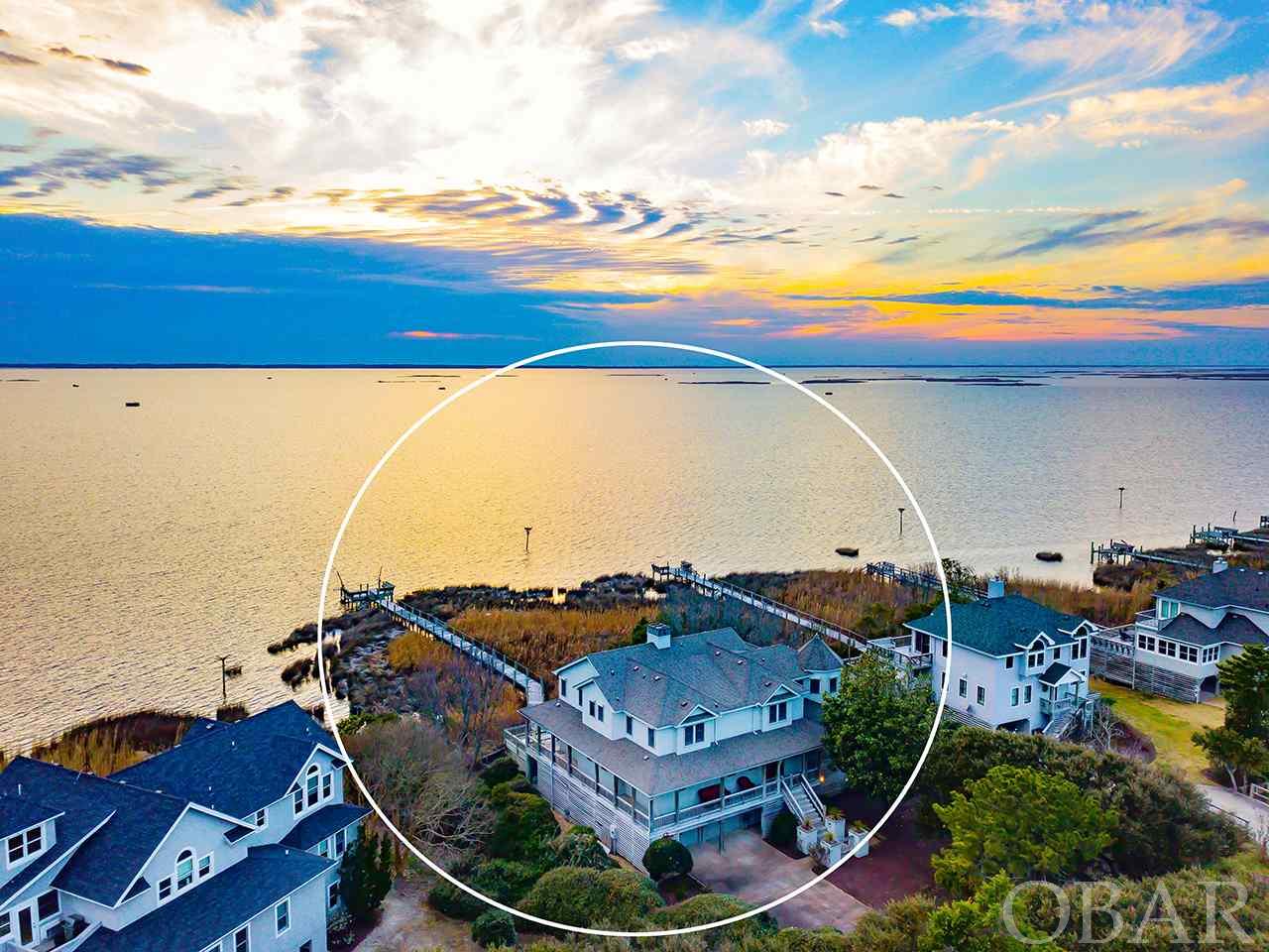 Waterfront Living at its Finest!  Never been rented and still occupied by the Original Owners, this Ken Green Custom Built Soundfront home in the Sanderling has endless bells and whistles.  The minute you walk in in the front door, your eye is immediately drawn to the custom stair handrail and custom trim work details...stunning!  The main level boasts a Sound View Master Suite, Living Room, Dining Room, Eat-In Kitchen, Walk-in Pantry, Powder room, and Laundry Room.  The Living Room features details including a Custom Mantle, Brass Sconces and Marble Surround Gas Fireplace, Built-in Cabinetry, Baseboards, Crown Molding, and French Doors to the Sound Front Covered and Sun Decking. The Dining Room is also impressive with more Custom Crown Molding, Baseboards, Wainscoting, Brass Chandelier and ceiling Medallion, Sun block shades, Sliders to the Sound Front Decking and even a Glass Pocket door to the Living Room (Kitchen also has Pocket door to Living Room, so you can essentially close off Dining and Kitchen from Living Room if desired).  The Chef’s Kitchen was REMODLED in 2012 and brings even more wow factor with a Walk-in Pantry, Custom Crystal Cabinetry, Stained Glass Windows, Corian Countertops, a Carrera Marble top Island, Wet Bar, Tongue in groove Cypress Ceiling, and Stainless appliances including a Gas Wolf Range and Wolf Electric Under Counter Oven, Sub Zero ALL Refrigerator (2nd Sub Zero in Laundry Room is ALL Freezer) and Ice Maker, and Kitchen Aid Dishwasher and Trash Compactor.  Be sure to ask your agent for a complete home features list found in Associated Docs!  The main level Master Suite also features sliders leading to the Soundfront decking, Cypress Wainscoting and Crown Molding, 2 Custom Walk-in Closets, Double Vanities, Stand Up Tiled Shower with double shower heads, Kohler Fixtures and Whirpool Tub, Custom Stained Glass Windows, and classic black and white tile flooring.  Many of these stunning bathroom features are also found in the Powder Room on this level.   The 2nd Level is ideally designed with a spacious Family Room complete with Vaulted Ceilings, French Doors to another Soundfront Deck, Sun Shades, another Wet Bar, an Under counter Sub Zero fridge/freezer, Sound System, and glass pocket doors to close off the room from the hallway, if desired.  There are 3 additional Master Bedrooms on the 2nd level, each with its own private full Bathroom, a ‘hideout’ custom painted bunk room,  as well as a ‘hidden’ private Office.  There is no lack of storage in this home as you will find cedar lined closets throughout including the Ground Level Mud Room.  The Ground Level also offers a spacious half Bathroom (accessed from outside) with a direct drain dehumidifier, 2 Large Outside Showers, a Fish Cleaning Table with Double Sink, 4 car enclosed Garage, Fridge/Freezer, and 2 additional storage closets (perfect for beach gear!).  ADDITIONAL HOME FEATURES include: 2 NEW HVAC Trane Units (inside Air Handlers and outside Heat Pumps) Jan. 2021; Oak Hardwood Flooring; Casablanca Ceilings Fans; Aluminum roll shutters on all windows and doors; 15,000kw Generac Generator; Hydraulic Elevator; Spa/Hot Tub; 6 Zone Irrigation System; Two Hot Water Heaters; Security/Fire Alarm system with 2 exterior cameras; Central Vacuum; Bulkhead; Private Walkway to Sound; Private Dock w/ Davits (no motors), Water and Electric; Lightning rods; Driveway lights; Gutters and Downspouts; Low E Andersen windows; 6” Exterior Walls; Structural steel beams along length of house; Manufactured roof trusses with hurricane straps; Manufactured floor joists for extra strength; Frost proof hose bibs (mid and upper level); Regular bibs and foot washes at ground level; Hurricane locks on Garage Doors; NEW ROOF about 10 years ago; Dog Enclosure.  Truly a rare find on the Outer Banks, NC!  MATTERPORT TOUR LINK: https://my.matterport.com/show/?m=wiNKNSGEJpX&brand=0