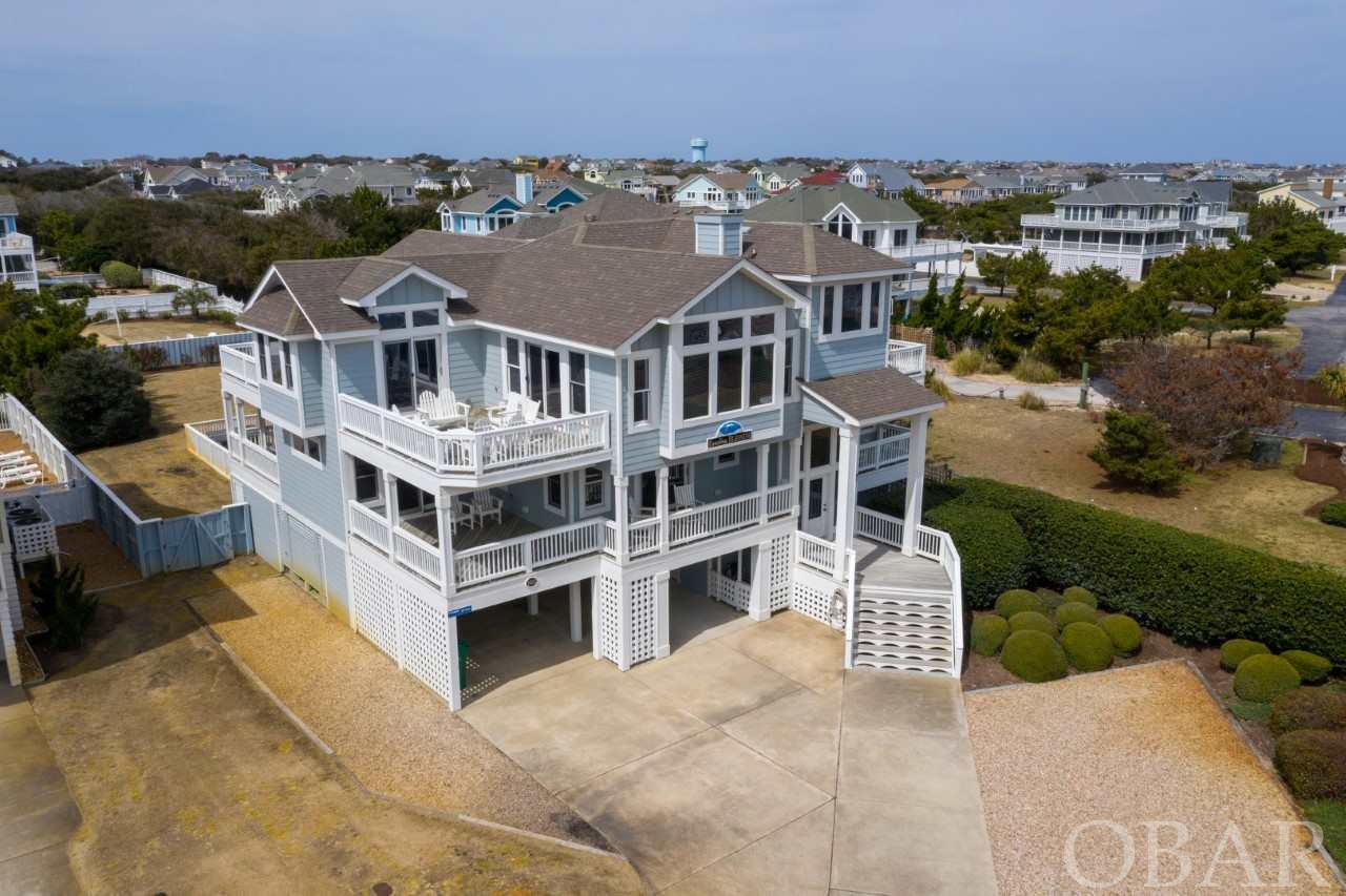 This is a rare opportunity to own a home of this size and capacity in the Town of Duck! Enjoy ocean views and direct ocean access to the beach without the additional risk and maintenance of ocean front! Four Seasons is top shelf! The owners and the association ensure that the neighborhood is always safe and sharp. Everyone loves the large outdoor community pool that is nearby. The indoor pool and fitness center boost rents and make the shoulder season a winner! This home has good looks and a spacious plan that is sure to please. The warm heart pine floors, abundance of windows and cathedral ceilings make the open living area on the top floor feel stylish and special. Choose between a sundeck with ocean views or the screen porch and sundeck on the west side overlooking the pool and lovely landscaped yard with a grassy playing field. The elevator takes all of your guests and groceries to this top level which also has two king bedrooms with en-suite baths. The ocean view loft is a favorite spot for reading. The mid level features 6 bedrooms, one of which can also be used as a den. On the groundfloor there are two more bedrooms with en-suite baths. The gameroom/media room on the ground floor is huge and features a pool table, an arcade game, a large tv and a kitchenette with a full size fridge. This room also has direct access to a large shaded area adjacent to the pool. The outdoor living are is perfect for large gatherings and large fun! There is plenty of shade and also plenty of sun since the pool is on the west side. The huge grassy lawn is perfect for games and sports and this is a rare and valuable amenity. Rental projection on file $242k
