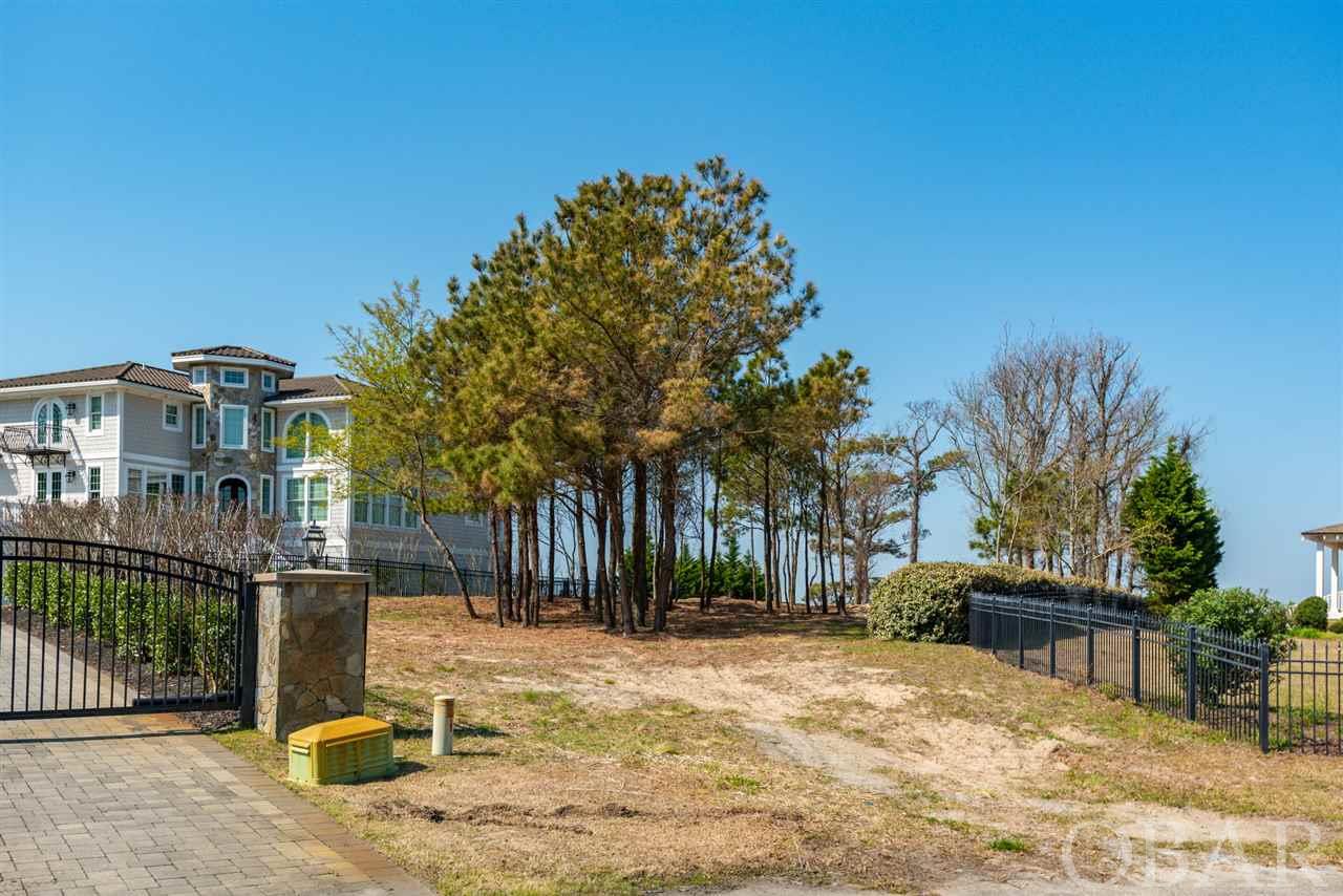 On a spectacular elevated vantage point, with outstanding panoramic views, a once-in-a-lifetime opportunity exists to own an enviable estate lot on the Currituck Sound in the idyllic seaside hamlet of Duck, North Carolina, which consistently earns accolades and rankings such as "Best Coastal Small Towns" and "Top 15 Family Friendly Beaches in America." Graced by towering trees overlooking the water, where ospreys perch keenly watching the abundant  wildlife that flourishes all around, this location is a nature lover's dream. A private and serene property with more than 75 feet of water frontage, with enough elevation for possible distant ocean views as well, it is flanked on both sides by several of the Outer Banks finest homes, and is one of the last soundfront lots in Duck suited as in ideal location for a grand waterfront estate home. The building site is over 22,000 sqft and can accommodate a substantial home, pool and grounds. Duck's famous shopping, some of the area's best restaurants, coffee shops and spas are just a stroll or bike ride away. The beach is also a hop, skip and a jump away, as are the more convenient everyday stores and necessaries of Kitty Hawk and Kill Devil Hills. This land awaits its transformation into a custom dream estate that will cradle residents and their guests in luxury.