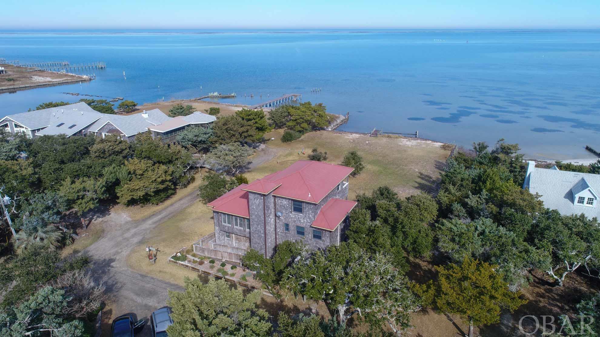 A beautiful, spacious, 4 bedroom/2 bath, 3-story home on a huge lot directly on the Pamlico Sound! This home has it all-a Trex ramp leading to 1st level, an elevator, new hurricane-rated windows looking out to the Sound, an additional living area with "murphy bed" on 3rd floor, a whole-house generator, and gas on-demand hot water heater. Unique hard wood floors, luxury vinyl on the first floor, custom tiling in the bathrooms and kitchen. An abundance of windows gives natural light and 2 covered porches with striking western red cedar ceilings  offer an unobstructed view of the sound- perfect for watching the passing boats and bird-watching. Large eat-in kitchen with custom cabinets (Hatteras Originals made in Frisco), stainless steel appliances, gas stove, granite counter-tops and a back-splash with hand-made tiles. Custom walk-in closet. There is a nice grassed yard leading to more than 100' on the Pamlico Sound- with a bulkhead with a small dock. The home was built in 3 stages- beginning in 2006, finishing in 2009 and sits on over 21,000 sf at the end of a private road in coveted Sound Shores. Metal roof and sprayed insulation in all external walls, roof and floors.