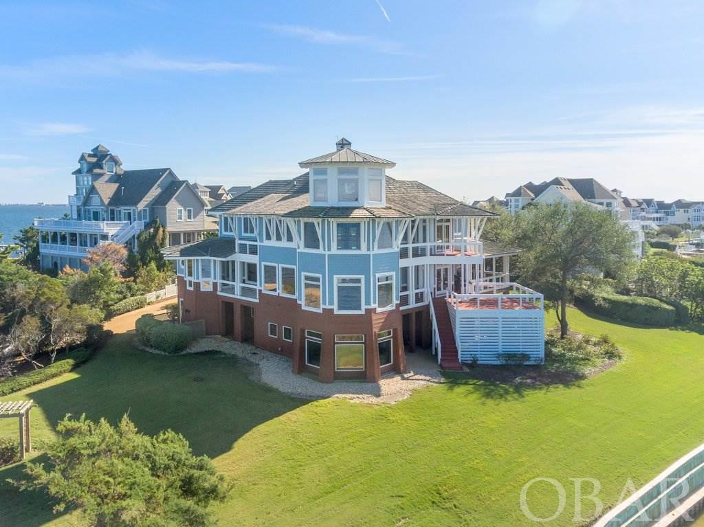 Premiere location and home in prestigious Pirate's Cove - with over 1.08 acres, this custom-built home was engineer designed for its waterfront location and proximity to the community world-class fishing marina.  Designed with soaring windows and airy rooms, this 5BR, 4.5BA three-level home showcases 270 degree water views and roomy lot. Interior features include: cathedral ceilings, tri-level tower, ship's watch, elevator, wine cellar, sauna, granite counter tops, hardwood floors, his/hers master bathrooms, gas fireplace, and bi-level living room areas. Designed with an eye-to-detail and sold furnished, this house was framed with exterior walls built with 2x6 stud walls, special insulation technique for energy efficiency, and treated pine shake shingles. Positioned on a bulk headed lot with additional breakwater walls, the landscaped grounds showcase the OBX island and offers access to excellent inshore and offshore fishing.  The prestigious Pirate's Cove community offers amenities that include two swimming pools, clubhouse, tennis courts, fitness center, commons area, world-class fishing marina with on-site restaurant and miles of perimeter docking perfect for walking or fishing.