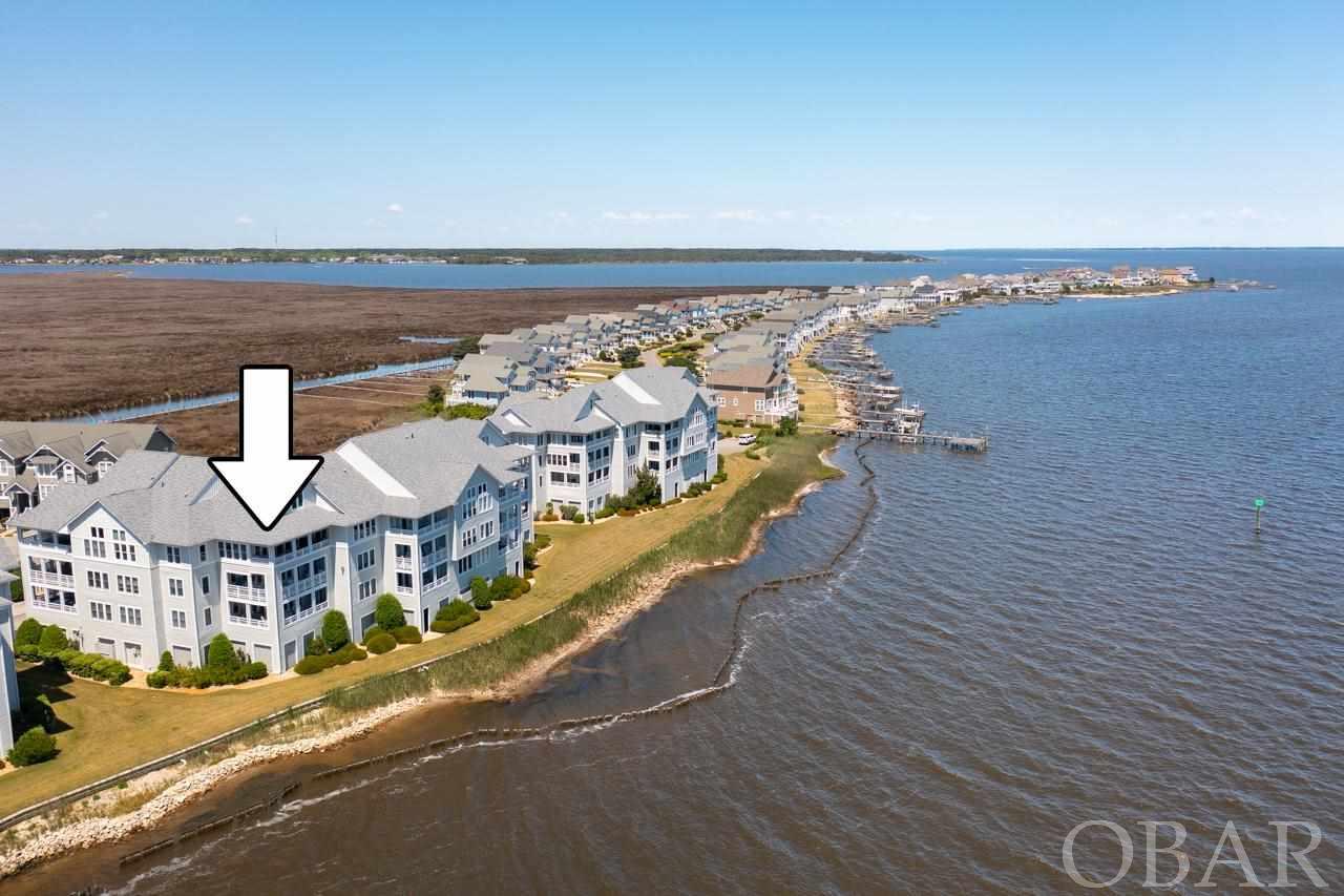 Beautifully updated, TOP FLOOR,  Southeast,  END UNIT with Unobstructed Sound View!  No other condo on the Outer Banks can compare to 1332 Ballast Point Villa in Pirates Cove.  Remodeled in 2012 by the current owners, this 2077 sq. ft.  four bedroom condominium offers a luxury waterfront lifestyle.  Four bedrooms, two and a half baths with the fourth bedroom redesigned into a study with built-in shelving, custom exotic wood desk and powder room. The study could be converted back to a guest bedroom if desired.  Beautiful WALNUT FLOORING throughout.  All new cabinetry by The Cabinet Company of Virginia with quality granite on all counters and Travertine tile kitchen backsplash.  All appliances were replaced at time of remodel to include new Bosh dishwasher, U-line Icemaker and Kitchenaid refrigerator except Thermador gas stove and double ovens.  In addition to the appliances, the hot water heater, bathroom fixtures, and two zone HVAC systems were also replaced.   Travertine fireplace face wall with built in Regency Horizon Contemporary 42”, 24,500 BTU insert gas fp unit will keep you warm and cozy during cooler months. During the construction of the building, the corner portion of the deck was enclosed to expand the living room area.  Double slider doors with one stationary, span of windows and corner windows showcase the most beautiful sunrises and twinkling Nags Head lights at night overlooking the Roanoke Sound.  Relax and enjoy the Surround Sound system throughout the home including the private deck while watching the fleet of boats come in to the harbor.  One of the few condominiums with its own storage/garage door unit. Owners and guests enjoy dining  at Bluewater Bar and Grill, cocktails and music at Mimi's Tiki Bar overlooking Pirates Cove's World Class Marina.  Pirates Cove is located in a gated community with amenities including a clubhouse/pool, owners pool, lighted tennis courts, playground, volleyball court, basketball court, fitness center, playground and miles of lighted docks to walk on.  A list of excluded personal property by a separate Bill of Sale in Assoc. Docs.  Water softener, freezer and EZ Go Golf Cart included. This condominium has a 30' dock assignment, #111 in protected Ballast Point canal and can be transferred to the new owner who qualifies with a registered vessel in new owners name.  This condominium is DEFINITELY IMPRESSIVE and sure to not last long.  Call the listing office today to schedule your private viewing.