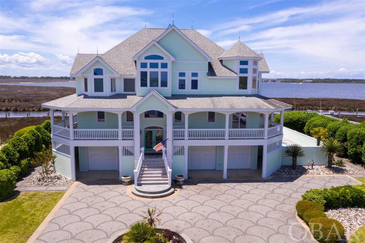 This amazing waterfront home offers gorgeous views of Shallowbag Bay and the Roanoke Sound! Quality, over the top construction, features elevator, private pool, top floor great room (wet bar, FP, built-ins) with an incredible master suite w/custom tile shower, two walk-in closets & jacuzzi tub for superb one level living! Well appointed, custom designed this home also features a mid-level living area w FP & wet bar plus a first level rec room for fun & games. All levels offering breathtaking views. Elevator operates from the ground level up. A well designed kitchen w butler pantry & spacious dining makes entertaining fun and easy. Beautiful 18 inch tile flooring throughout living plus IPE decking (looks like Teak) around the home. Check out the Cobblestone driveway! The 3 bay garage is tiled & climate controlled with a large work station. Home is wired for a generator and offers central vacuum throughout the home. Wrap around decking and porches to take advantage of every viewpoint or time of day! Have a dip in the refreshing private pool, hop on the boat for a trip to the gulf stream, or take a short drive to our pristine local beaches! There is a 35' slip reserved for your boat w power & water at the dock. Pirate's Cove is a premier waterfront community and the neighborhood of Ballast Point is the cream of the crop! Enjoyed by sportfishing lovers and outdoor enthusiasts alike. Cruz your golf cart down to the full service marina to eye the days catch, enjoy a cocktail or dinner at a restaurant onsite or take a stroll down miles of scenic boardwalks within the community. Tennis, fitness center and owners only community pool are here for your health and enjoyment. Just minutes away from the quaint town of Manteo, with activities & sites to see all year-round. Come discover Pirate's Cove and all that this wonderful home has to offer!