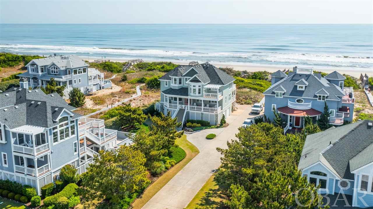 Stunning & completely renovated first tier oceanfront home in the sought after Buck Island community of Corolla. A Griggs & Cozy Kitchen custom remodel, this professionally appointed home boasts coastal elegance through & through. On the top floor, enjoy panoramic views of the Atlantic from the surrounding windows of this spacious open concept living area with built in cabinetry w/ beadboard backsplash & 12 foot ceilings, gas fireplace, wrap around seating, hardwood floors, and a half bath. A gourmet kitchen with Thermador range & microwave, dual dishwashers, Kitchenaid ice maker, granite countertops, and spacious island & dining seating is ideal for large groups of families & friends to gather. A ship's watch with writer's desk serves as a great spot to unwind and regroup. The top level master includes direct deck access, a walk-in closet with built in shelving, and beautifully updated bath with beachy blue cabinetry, a dual sink vanity with quartz countertops, and a standalone tub overlooking the ocean, and shower. On the second floor, two king master en suites with direct deck access & walk-in closet, a spacious kid's room with duo built-in bunk sets, a queen bedroom, full shared bath, and laundry room w/ Whirlpool washer & dryer, a sink & storage.  On the first floor, enjoy the convenience of a dry entry just off the direct beach access and into the home's media room w/ full bath. A two-car garage w/ full size refrigerator holds cars, bikes, surf boards, and everything in between. The Buck Island gated community includes overflow guest private parking, beachside cabana with restrooms and showers, an Olympic size swimming pool, spa, baby pool, basketball, tennis & more! Enjoy the convenience of Corolla's local shops & restaurants just a short walk or bike ride away. Closing to occur after 8/1/21