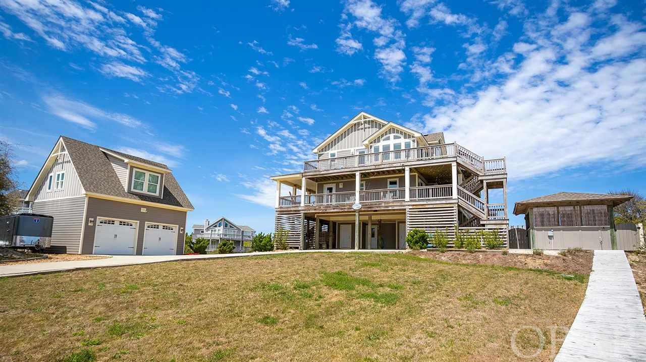 Rare opportunity for ownership in the Historic Corolla Village on a spacious semi-oceanfront parcel just steps to the beach, Currituck Beach Lighthouse, Whalehead Club & Currituck Heritage Park! This custom-built, Florez and Florez designed and meticulously well-maintained estate was built in 2012 and used primarily as a second home until joining Twiddy's rental program just a few years ago. On the top floor, a spacious great room w/ ocean views, built-in cabinetry & gas fireplace, a gourmet kitchen with dual stainless steel GE appliances, island, dining & breakfast seating, granite countertops, a half bath, and master suite with dual vanities & dual custom tiled shower, a private washer/dryer & direct deck access. On the second floor you'll find three master suites, a spacious bedroom, full bath, laundry room, and second level den w/ ocean views. The ground level is the perfect place for the kids to relax and unwind as it includes a kid-friendly room w/ three bunk sets, a full bath, game room w/ pool table & kitchenette w/ full-size refrigerator & wet bar. Enjoy the homes extensive list of outdoor amenities to include a 14x28 heated pool, poolside cabana, hot tub & outdoor showers, in addition to the professionally landscaped grounds with irrigation system. A detached guest house with 25'x25' two car garage, a queen bedroom, full bath, kitchenette & den is the perfect place for friends or family to enjoy additional privacy! House and detached garage come with a full set of custom made armor screens wind abatement system.  Enjoy the convenience of the Carotank Beach access just steps away, as well as, local shops & restaurants.