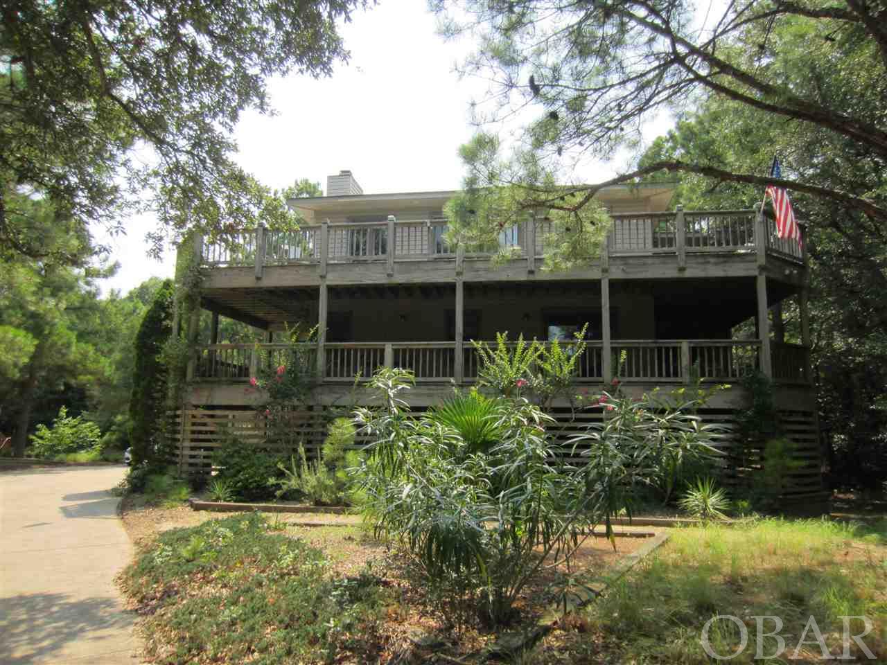 Gorgeous high elevation 4 bedroom, 3.5 bath home on the dunes of Southern Shores. Tucked back in the Live Oaks from the road. Very private. A huge number of decks!!! Two levels of extra wide decks go almost completely around the home. Sought after X Zone, so no Floor Insurance required. Open spacious living area with cathedral ceiling and an extra wide Andersen Slider out to the huge decks and an attractive, wood burning fireplace which owner says puts out a lot of heat. Beautiful, conveniently laid out kitchen with striking high-end Cherry cabinetry and granite counter tops. The Sky Light brings the sunlight in. Off of the kitchen is a super inviting 10 X 16 Florida Room. The windows are the kind that come almost down to the floor so they make you feel like the outside has come into the room. There is a pass-through from the kitchen with its own little pocket door. This heated and cooled room is fantastic. Attractive tiled powder room with sky light. There is a master bedroom on the southwest corner of this floor with its own door out to the decks. Elegant master bath with a stand-up shower and separate standard sized tub. The tile work in here is lovely. This bath also has a sky light. The middle floor has two bedrooms that share a lovely, renovated hall bath. Note the built-in window seats open for storage. There is another master bedroom with a gorgeous, tiled bath, slider out to the decks and walk-in closet.  The washer and dryer are located conveniently in the hallway. Also, there is an office on the northeast corner. One of the many great features of this home is the convenient DRY ENTRY underneath from the spacious under house parking. Enter the home without getting out in the weather. There is a huge area underneath fully paved, expansion would be easy. LOTS OF POSSIBILITIES for this wonderful area. There is also a large storage/workshop area that has a HVAC vent for cooling and heating, not counted in Heated Living Area. Outside shower. Whole house intercom, central VAC. Roof replaced 2004. Orkin does an annual inspection. Hoy HVAC services the heat pumps twice a year. Septic was just pumped August 2019. Long winding driveway with a huge parking pad for plenty of parking. Just a quick walk to the Hillcrest Traffic light and the Hillcrest Beach Access. Look in Associated Docs for MOG/RPD, Expenses, As Built Survey and Permits. For a low $65 per year the Southern Shores Civic Association lets you take advantage of three sound side marinas with picnic and crabbing areas, Private Sound Beach, thirty-four Private Ocean Beach accesses, parks, basketball and soccer fields. For an additional fee you can join the SSCA tennis courts and/or Boat Club.  Owner occupied, EZ to Show! Combo Lockbox. Some furniture items may convey.