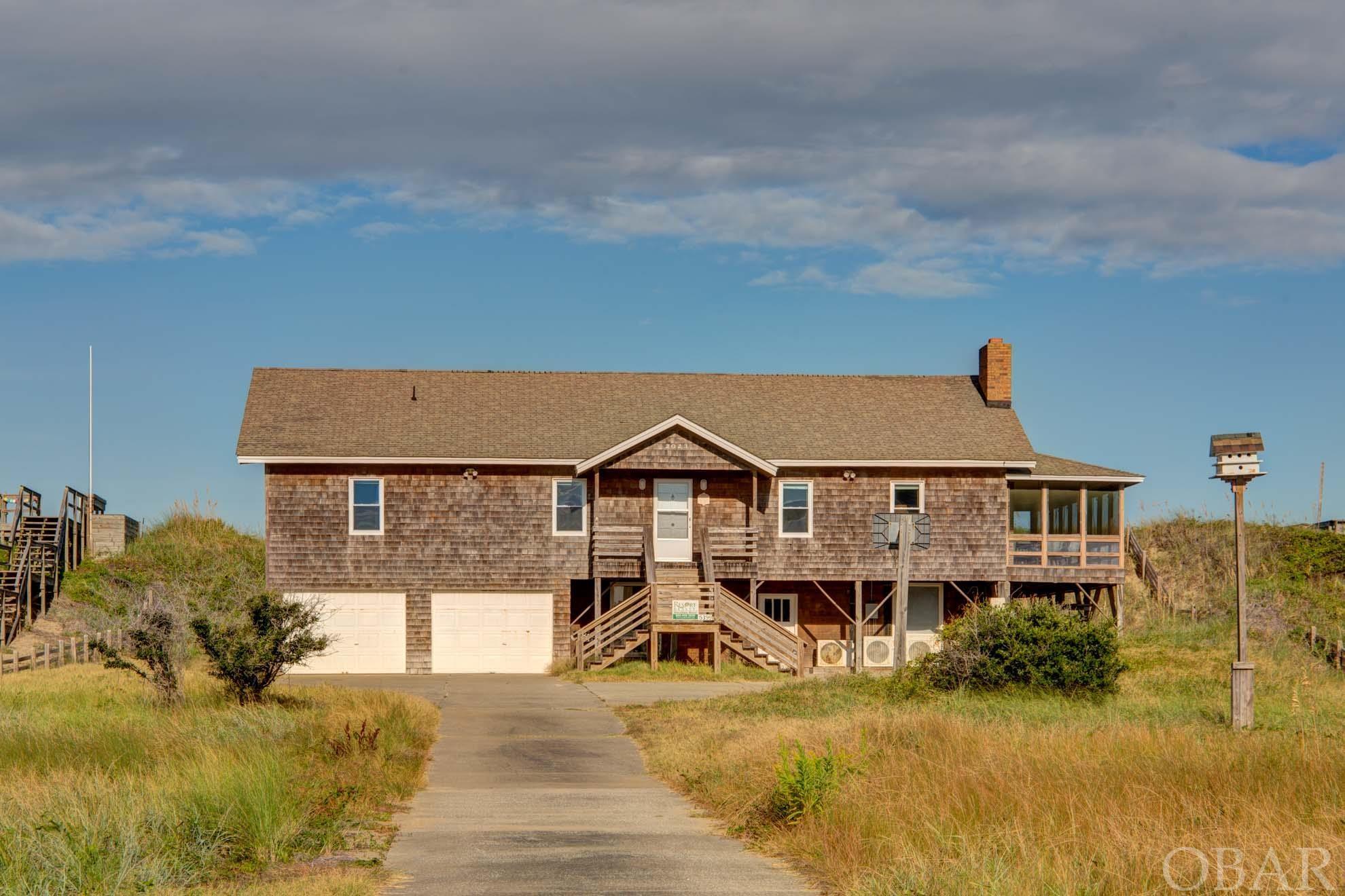 This vintage oceanfront cottage tucked into the dunes provides a rare opportunity to own nearly an acre of oceanfront land on a 100-foot wide lot. The value of this property is in the land and the development potential. Subdivide into two oceanfront parcels, tap into the sewer system (KDHWWTP) to develop a cottage court or larger home, or restore the classic OBX cottage for the enjoyment of generations to come. This property is conveniently located near the Nags Head & Kill Devil Hills town line and is within walking distance of local restaurants, breweries, and groceries.    Built-in 1970, the cottage has 4 spacious bedrooms - 2 bedrooms with ocean views, and 2.5 bathrooms. Tall cathedral ceilings and an approximately 500 square feet screened-in porch with ocean views add to the charm and character of this classic beach cottage.  The healthy dune system adds privacy and ambiance to the oceanfront decks and beach access. The property has an X flood zone west of the dune and a VE flood zone on the oceanside of the property.   This home was used as a second family home for decades and has recently been on the vacation rental market with a conservative rental history of $50k.