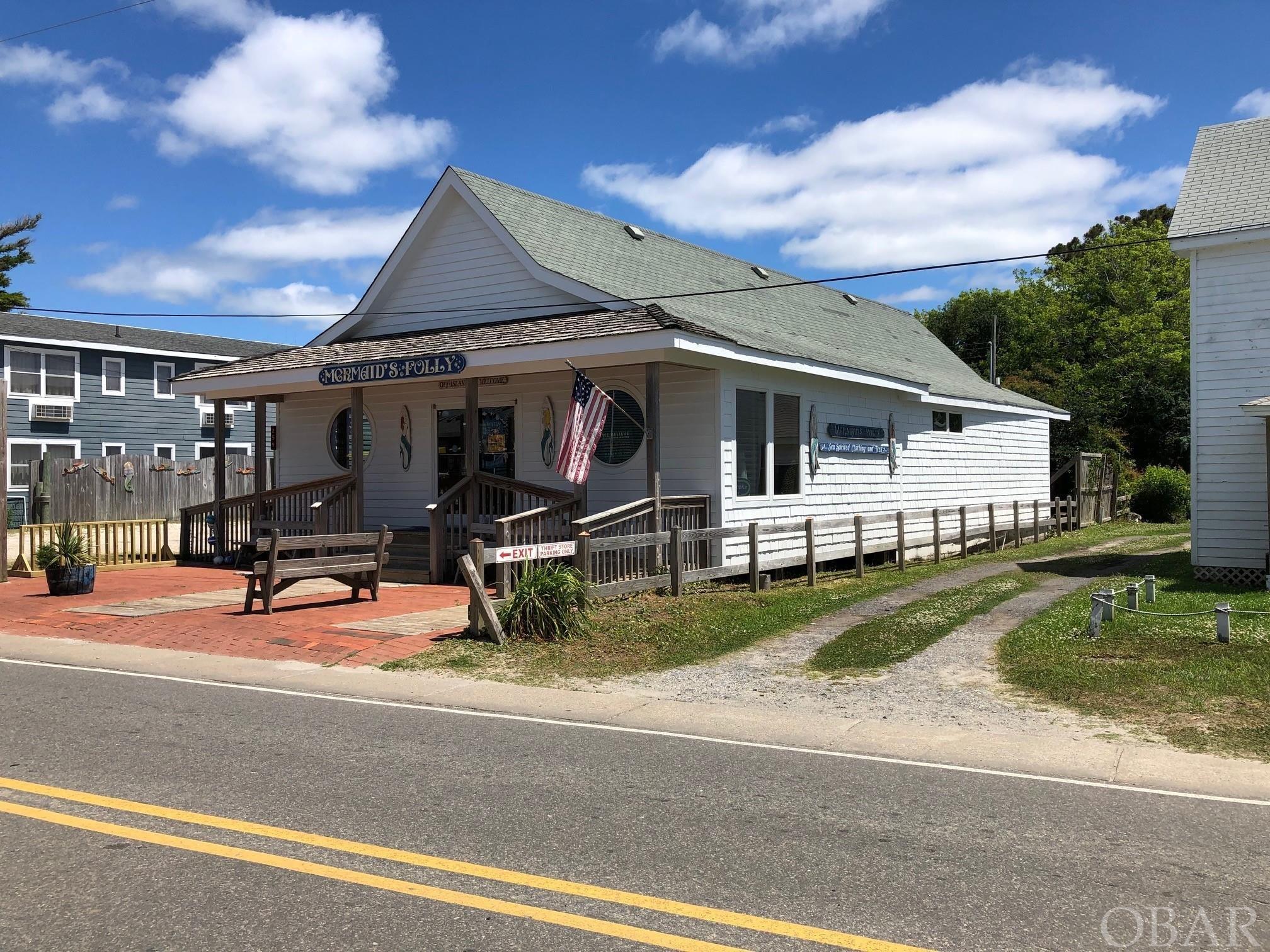 A unique retail building with a brick patio entrance and large welcoming round windows. You can't go by without stopping in! Centrally located in "downtown Ocracoke" with great walk-in and vehicular traffic! Within walking distance of the arrival and departure docking area of the passenger ferry. To add to the walk-in traffic, an island tram stop is located across the street. Currently being used as successful retail shop (Mermaid's Folly). Amenities include wood floors, vaulted ceilings with wooden beams, ceiling fans, track lighting, wood walls, office with 1/2 bath, central heat /ac, dressing rooms and a custom built wooden check out counter. Cedar shake exterior, partially fenced yard, side parking area and small storage shed.  2000 square feet of beautiful retail space! The business/goodwill/inventory/merchandise fixtures do not convey; however, they may be purchased separately.