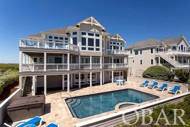 181 Cottage Cove Rd, Pine Island: everything you would want in an upscale Outer Banks oceanfront home; exclusive '1 home' per 90' of oceanfront location, offering dramatic unobstructed ocean and sound views in a safe, elevated, preferred X-flood zone location, classic, stylish custom designed and built home, with a great open floorplan, elevator, rec room, theater room, upscale heated pool & spa, in excellent condition, and very importantly, with modern, all updated exterior cladding. IE: modern 2016 roof, updated entire exterior facade with cement shingles and pvc trim 2016, 60%-70% newer windows as needed and all new sliders 2016, areas of new Trex decking 2021, and brand new high end pool remodel with Travertine paver pool deck 2021; repeat, all new siding with 18" cementitous shakes, pvc trim, soffit, fascia, gutters, all valuable and important updates! Upgraded bluetooth audio visual & system 2022 with new theater tv, 2019 hot tub, 2021 kitchen appliances, fresh interior paint, among other updates.  Grand and open great room offering panoramic Ocean and Sound views, gas fireplace with 'coquina' and limestone surround, open foyer, gleaming oak hardwood floors on all of the top 2 levels and stair treads, custom trim, 7 large master bedrooms, comfortable bathrooms with all granite tops, quality glass topped furnishings, comfortable recreation room with billiards table, seating, &kitchenett e, huge pool deck and ample outdoor furniture.  2 levels of decking front and rear for shade and sun, ample parking areas plus 2 garage's (one for guests one for owner), lots of owner storage, mature stable landscaping easy to maintain, and solid, stable, vegetated dune line with new private beach access walkover.  This property provides likely the most private, quiet beach in the area, with one home per 90' of oceanfront property, and sunrises and sunsets to die for.  High income producing property, with $288,302 projected gross rental income, and well on it's way with 2022 rental bookings (rental reports available).  This home is ready for immediate enjoyment, is truly in great condition, really shines inside and out, so the new owner will benefit from all these updates and efforts.  This property will be a pleasure to own and enjoy, act now to capture the seasons income and years of enjoyment!