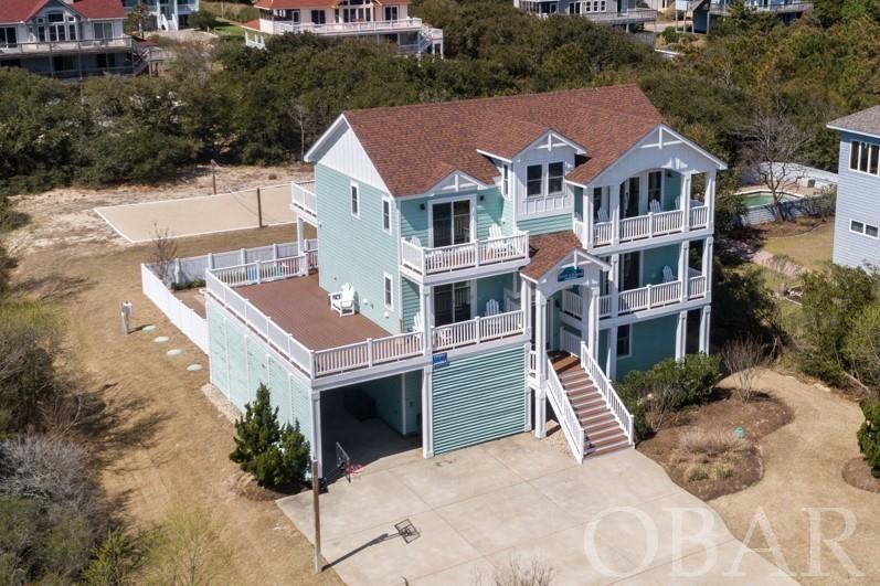 This vibrant 7-bedroom Oceanside home has attracted guests for the last 6 years with its wonderful location, amenities and pristine interior professionally designed and decorated. This cottage offers a welcoming place to entertain and enjoy time together on the Outer Banks. Located in the Whalehead community, this home is within walking distance to the beach access. New owners can immediately move in and start enjoying the charms of living in Corolla with its shopping, restaurants, wild horse tours, golfing, Currituck Lighthouse, wildlife center at the Whalehead Club just a few minutes ride away.    The home has a welcoming appeal with its sunny exterior, large light reflecting windows and sliders, allowing natural light to pour in. Windows are Impact Resistant Double Hung Jeld-Wen Vinyl Series. Spacious sun decks with Trex decking and Polywood furniture.  Inside on the top level is a great room with soaring cathedral ceilings and sparkling white walls.  A well-equipped kitchen with 2 Large Refrigerators with ice makers, 2 wall ovens, 5 burner cooktop. Granite and quartz countertops and island provide a wonderful prep area and additional seating. This open concept space also includes room for a dining area with built in bench and living area with gas fireplace. A few steps up is a cozy reading loft where you can catch a glimpse of the ocean from the built-in bench with storage. Primary en suite bedroom with soaking tub,  tile shower and seamless shower door, private access to the deck is also on this level. The mid-level hosts 2 bedrooms with private en suite bathrooms, one with tub, one with shower with seamless shower door, both have deck access.  Bedroom with custom built-in bunks with lighting and additional bedroom with deck access share the hall bath.  One set of stackable washer/ dryer on this floor, 2nd set on rec room level.  Downstairs is a wonderful rec room with pool table, 2 flat screen TV's (one small, one large on opposite walls for maximum viewing) a wet bar with refrigerator and microwave.  Another bedroom with a en suite bath and one that shares the hall bath.   Entertaining is made easy outdoors with the large 16’ X 30’ pool with sun ledge, tiki bar, sound system, hot tub and outdoor shower. A fence surrounds the pool area.  Just on the other side of the fence is Volley Ball. There's a basketball hoop in the front of the house.   This home’s desirable amenities and features including theater room with stadium seating have made it a favorite destination for vacations.   High Performing Rental with over $127K already booked for 2022.  All you have to do is look at the house to clearly see the pride of ownership and how this home has been lovingly kept.