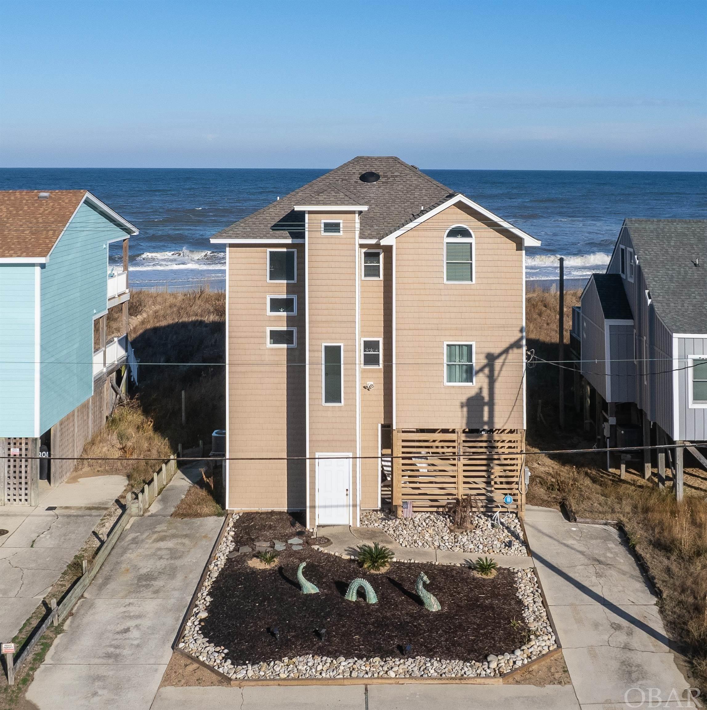 This beautifully updated, 3 bedroom oceanfront home has 2 additional bonus rooms with closets and is nestled in a vegetative beach dune in the heart of Kill Devil Hills. Located just south of the Avalon Fishing Pier, you are steps to shopping, dining and festive night life.  Bask in the oceanfront, oversized sun deck or cross boardwalk over dune onto the beach where you can surf, swim or fish in your backyard. Exquisite 2021 kitchen caters to your inner gourmet chef with luxurious appliances by Wolf. Prepare fresh seafood in the convection steam oven, crisp veggies on gas cooktop or warm up dessert in built-in microwave drawer. LG Stainless steel refrigerator has bonus glass door on front for drinks and snacks.  Full overlay custom cabinetry by JEK features full extension, slow close, dovetail drawers, solid wood cabinet doors and a crisp shaker white finish. Much love and thought was poured into new luxury vinyl plank flooring, custom tile showers and bathroom floors, new vanities, faucets, interior doors, trim, paint, custom blinds and luxurious furnishings that capture the essence of elegant beach decor.  Ride elevator or take stairs to Top-level which boasts vaulted ceilings and copious ocean views. The en-suite bedroom has iridescent inlayed accent tile shower. Down the hall, there are two gracious bedrooms that share hall bath with custom tile shower.  Mid-level sits just above dune for gracious ocean views from kitchen, dry bar and living room.  Hall bathroom with custom tile shower passes through to oversized guest bedroom.  Ground level has game room with closet, bathroom with tub/shower and stacked washer and dryer.   Go straight from the beach to the unheated half bath near outdoor shower.  Ground level storage shed and storage box convey.   Tax records show 5 bedrooms and 4 baths.
