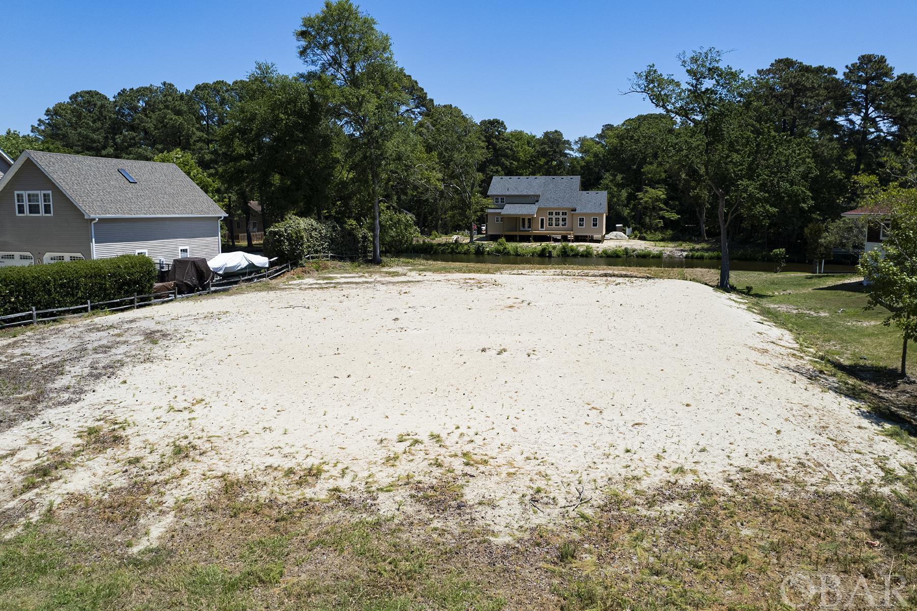 UNIQUE OPPORTUNITY of READY-TO-BUILD canalfront, bulkheaded land in Southern Shores. Build your dream Outer Banks home on almost half an acre, where ALL THE SITE WORK HAS ALREADY BEEN DONE for you. The owner has cleared the land, paid the water tap fee, completed a site plan, gotten a septic permit, had the land filled to the max at the time, and the building pad is level and ready to go! That's right, over $50,000 in site work has already been done for you, which saves you money AND TIME. Four bedroom septic permit on file. Owner filled the land to 7' above base flood elevation, the max at the time it was filled. Since then, the code has changed and another 1' could potentially be added (assuming the slope on each side meets the code.) The owner just had it bush hogged again, to clear any overgrowth. The owners planned to build their forever home on this land, which is why all the work has been done with precision. Sometimes life has other plans, and the owners have decided to change gears and let the land go. This lot is located in the town of Southern Shores, in a neighborhood that fronts a golf course on one side of the street, and a canal on the other. It's just minutes to the oceanfront, and the canal behind the home is navigable for a boat to get to the sound waters! The neighborhood is conveniently located off the beaten path but super close to shops, restaurants and all the waterfront beauty that the Outer Banks offers. By owning in Southern Shores, for a fee of $65/year, you can have access to the amenities of the Southern Shores Civic Association, including beach access with parking, soundfront beach, 3 soundside marinas with boat launches, playgrounds, basketball courts, soccer field and you can also choose to join the very active Southern Shores tennis club. But wait, there's more! The Duck Woods Country Club with its beautiful golf course, ample tennis courts, clubhouse, dining and more are right nearby! Don't let this one pass you by, it literally could not be any easier to start your dream build on this land.
