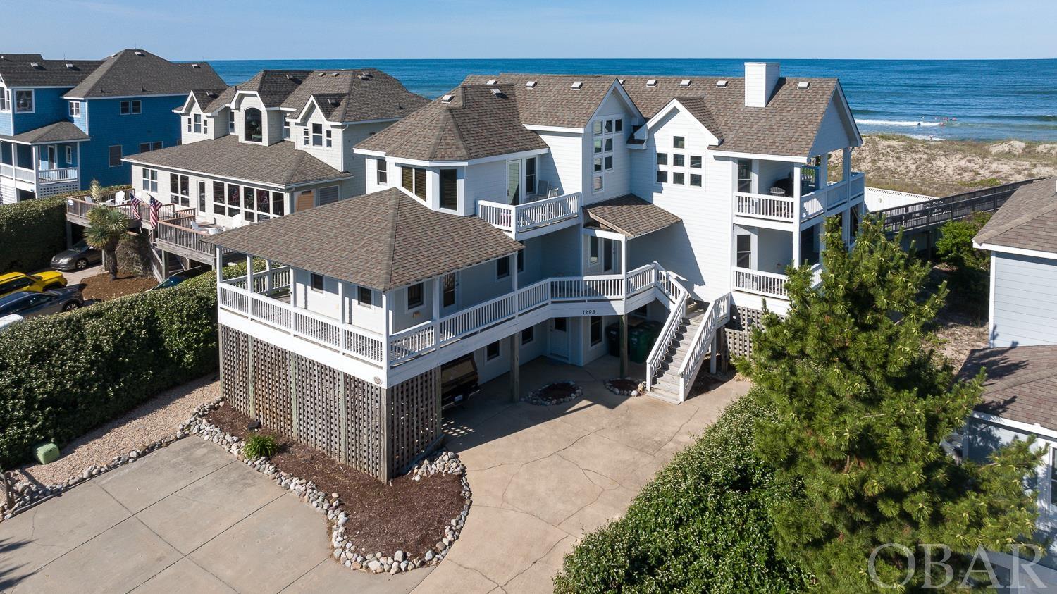 Ocean views abound at this 7 bedroom home in northern Corolla. Located on a huge, elevated oceanfront lot, this home was lovingly used only as a second home, and the house is NOT currently in a rental program (minimal wear and tear) but is projected to do over $296,000+ a year in rental income! The meticulous owners have been updating over the recent years with a HUGE heated concrete pool and spacious pool deck/cabana, a new kitchen with granite countertops and stainless appliances, select new siding and exterior paint, and newer HVACs. Well appointed and designed to take in the view, the home has a reverse floor plan with the top level hosting the open kitchen, dining and living room, all overlooking the Atlantic Ocean. The generous Oceanside decks on the top level and mid-level look out over the pool area and across the wide dune to the beach. On the third floor you’ll also find a half bath and an en-suite king bedroom overlooking the sunset views to the west. The mid-level has 4 bedrooms total, two of which have their own private bathrooms with Jacuzzi tubs, and access to the ocean-side deck. On the ground level you’ll find 2 more bedrooms, a recently remodeled full bathroom, and a large game room with kitchenette and plenty of room to add your own pool table, ping pong table or foosball table! From the rec room, step outside to enter the large fenced in pool deck with shaded cabana area or walk out on your own private beach walkway complete with dune deck area that provides yet another relaxing area to take in the view of the Atlantic Ocean. With ample parking, this home is a comfortable and spacious beach getaway that also provides a great investment opportunity! Located in the Villages at Ocean Hill, you're just down the street from the 4x4 beaches where the wild horses roam, and historic Corolla Village & Shops and even the Currituck Lighthouse! Also enjoy the premier Villages at Ocean Hill community amenities including oceanfront & lakefront pools, tennis, basketball and pickleball courts, year-round fitness center, and more! Furnishing updates/costs available upon request.