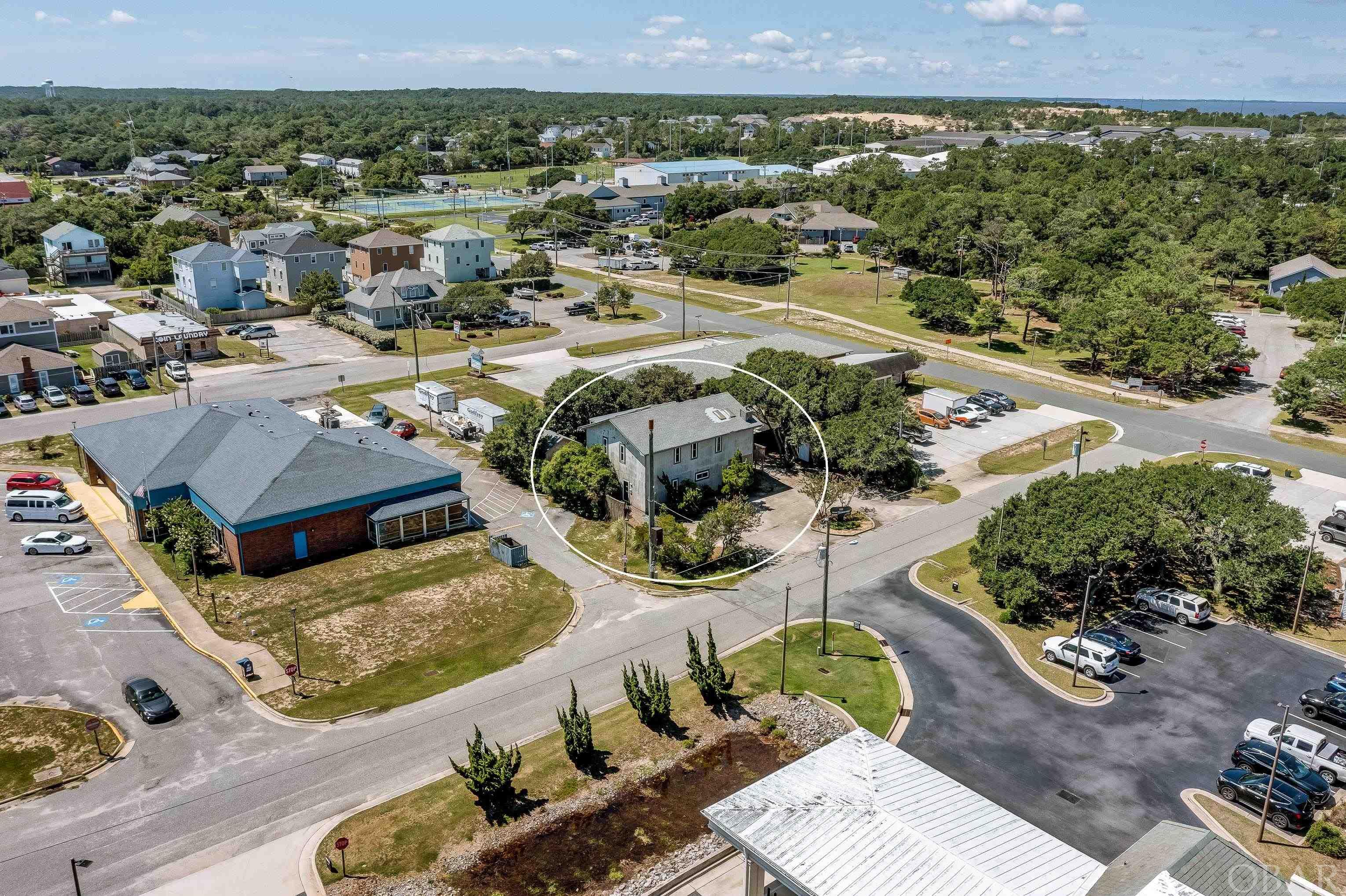Opportunity strikes with this super rare find of a mixed use Commercial and Residential building located in the heart of Kill Devil Hills. With 2,351 heated square feet and multiple options this one has a little bit of all the essentials. The top level offers its own entry with Three bedrooms, Two updated bathrooms, Living Room with a Contemporary style Gas fire place and Large Kitchen with a quality gas stove and range. Quality new tile plank flooring throughout the living and bathroom areas. Large deep skylights offer natural light while a glass block wall accentuates it all and creates a great ambience in the living spaces. An interior stairwell leads to the ground level which also offers two separate entry's and exits on the western and eastern sides, perfect for your business needs. This level is a commercial office space with multiple rooms including a large Kitchenette, Half bath and a utility room with washer, dryer and HW heater. This is truly a great chance to create your vison with a little TLC and some savvy creativity this will be a homerun and offers a variety of uses. Live and work on site as an Owner operator, rent the top floor and work out of the lower levels, Rent both floors for positive cash flow, Airbnb, Long Term housing, Student rentals or use entire building as your own….lots of great options. The Exterior yard space has plenty of green space, live oaks and locally sourced vegetation creating great curb appeal for an attractive business space. With a large detached workshop with power this property has even more potential and no lack of storage options. Centrally located and within quick walk or biking distances to Parks n Rec for some exercise, Brew Station for food and drink, Post Office for your partners Amazon returns, KDH multi use path to skate parks and ball fields and of course a stop light 2 blocks away with a fantastic beach access with showers and baths. Call me to discuss the possibilities.