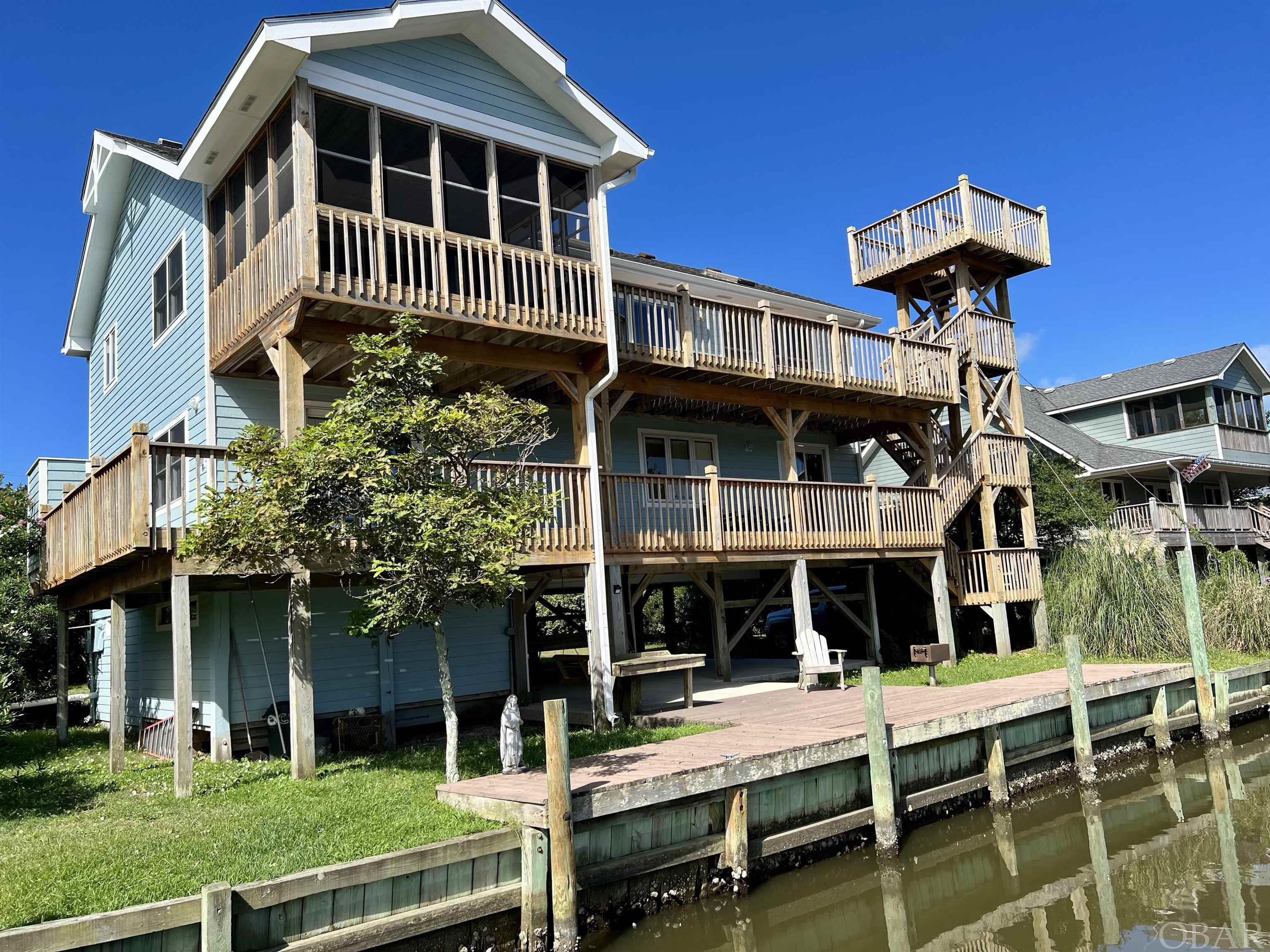 This custom built home ticks all the boxes for your perfect island retreat!  Located at the base of a canal providing deep water dockage and spectacular views extending out and over Pamlico sound.  Multiple two level decks, screened porch and an above roof level observation deck maximize your ability to enjoy this amazing location.  The house is a reverse floor plan with the downstairs containing four bedrooms and two full bathrooms.  Two bedrooms including the master look out over the water, master bath with jetted soaking tub offers same gorgeous view.  Upstairs is a wide open floor plan with cathedral ceiling.  Spacious living area, dining and open kitchen with lots of storage.  The second floor also offers a bonus room/office.  Underneath the house has concrete pad, a single vehicle sized garage as well as a large workshop/storage area.  The house comes equipped with Starlink satellite internet system (subscription transferable) as well a a Telsa HPWC high power charge port and Blink security cams (account transferable).  Sellers have meticulously maintained this property over the years and are including all furnishings making it truly a turn-key property