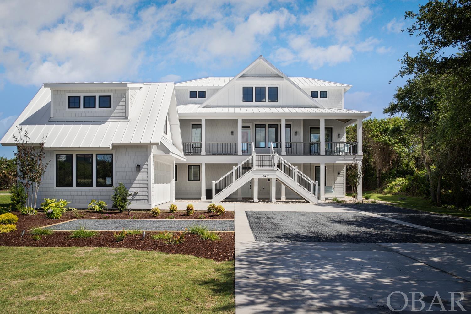 This exquisite new construction is just steps from the beach in a prime location within Duck Village. With luxurious, modern touches throughout, this custom made 7 bedroom, 7 and a half bath home has all the amenities you could think of. Thoughtfully designed, the main living space is on the middle level, with lots of large windows, plenty of natural light, and 18 ft ceilings. The open chef's kitchen, dining, and living room opens to both the front and back decks and flows beautifully to the master suite with large walk-in closet, dual vanity, freestanding tub, walk-in shower, and private water closet.  The staircase upstairs takes you to a lofted walkway connecting two more spacious master bedrooms with private baths on the third floor.  Three additional master suites are on the ground level floor, each with a private bath plus the laundry room. Also on the ground level is a large rec room with pool table, 2 Large TVs, Sonos Sound System, wet bar, extra sitting area, and direct access to the back yard and private pool area. The home offers great outdoor space all around, including a back covered patio near the pool and hot tub and tons of greenspace. A unique feature is a detached guest suite over the garage with covered access from the main house.  The guest suite features a beautiful iron king bed, and a wet bar with an under the counter beverage refrigerator and private bath.  Top quality construction with all premium products makes this home a step above all others. Special features include a metal roof, top of the line LVP Flooring by Greyne, Timbertech Composite Decking, an outlet for Electric Vehicle Charging Station and an Outlet for Golf Cart Charging, custom audio/visual system with Sonos speakers throughout, and a double outdoor shower.