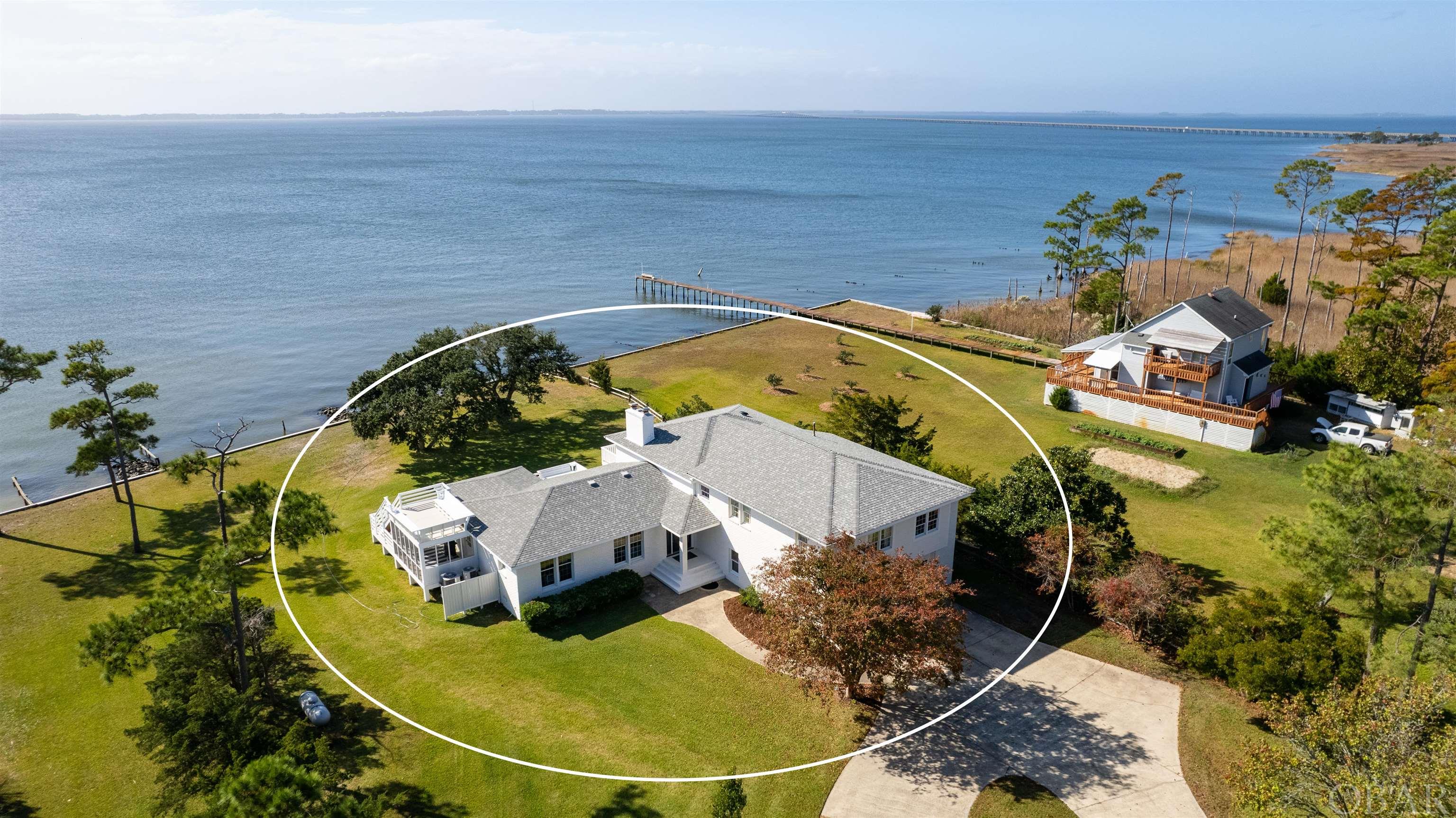 This property is one of those properties that truly do not come on the market often.   A gorgeous soundfront estate tucked away on the North End of Roanoke Island. The home has been well maintained and updated through the years.  At first glance you will notice the large parcel of land the home sits on.  A parcel that could be subdivided to add a guest house or second home.  The expansive views of the Croatan sound will take your breath away.    Walking into the front door the hardwood floors grasp your attention and pull you into the bright living area with panoramic  sound views. The massive kitchen provides tons of storage in the cabinets, beautiful quartz countertops compliment the ceramic tile floors.  The sunroom with kitchen booths are perfect for having breakfast or a quick lunch while watching the dolphins play in the sound. A formal dining room is the picturesque place to host friends and family for supper.  After supper move to the boundless porch area to enjoy a drink and watch the sunset, before moving back into the spacious living area featuring built-ins and plenty of space to spread out around the fireplace.  When it is time to retire for the night the Master bedroom is one of the largest on the island. This master retreat has two walk-in closets and a NEW beautifully equipped ensuite bathroom.  The three guest rooms also offer plenty of space as kid's rooms, and office, or for family to come to visit.  The 900 sq ft two car garage has plenty of space to house two vehicles, as well as plenty of extra space for storage without being cramped for space.  Just pass garage you will find the approximate 900 squ ft bonus space which offers three rooms that could be perfect as a separate apartment for airbnb, mother-in-law suite, or convert to your own home office.  This property is one of a kind and the location is yet another plus.  Just around the corner from the NC Aquarium, less than a 5 minute drive to all three schools, the Lost Colony, and the Gardens.  10 Minutes to the Ocean!  It has it ALL!  Updates include new roof in 2018, in 2022 - complete master bathroom remodel, screened in porch, sheetrock throughout living area, exterior & interior paint, new front door, decking, in 2007 septic replaced.  The home had the new addition added in 1998 to add an extensive amount of space.  There are several measurements from appraisals and the county tax site that states that the home is larger.