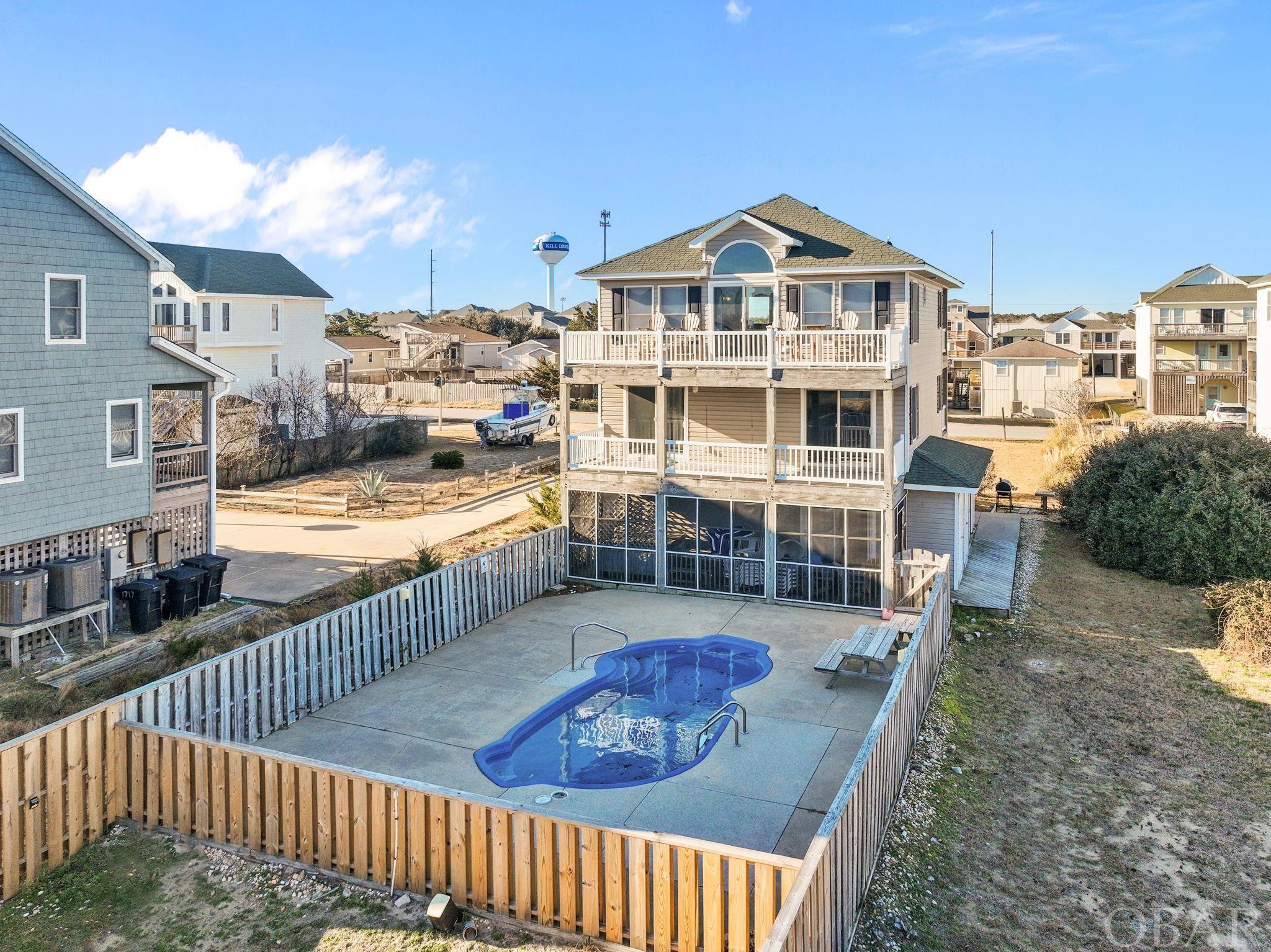 PRICE REDUCED!!! TERRIFIC LOCATION!! ONLY 2 LOTS OFF THE OCEAN!! In the heart of Kill Devil Hills, JUST MINUTES TO THE 3rd. St. OCEAN ACCESS!  This well maintained beach home has all the Bells & Whistles that make a popular rental home!  Outdoor Pool w/oversize deck area, hot tub, game room w/wet bar, large screened-in porch, multi-level decks! Huge lot (15000 sq ft) with extra space for entertaining or fun outdoor activities (volley ball, corn hole, etc.)!! The top level features a bright & open great room w/vaulted ceilings, gas fireplace, tons of windows and lovely hard wood flooring!  A powder room is also on this level. The mid level offers 3 nice size bedrooms and two full baths also w/hard wood flooring.  The east and west side rooms have access to decks.  The ground level features two bedrooms, a full bath, laundry area, and the game room which opens up to the screened porch overlooking the pool area! NEW in 2022- Laminate flooring, top floor freshly painted, New stove, pool pump, solar lighting for outdoors, water heater. NEW 2021- Pool converted to saltwater, new toilets, water filtrations for kitchen sink, new fence, bunk beds, king, lazyboy sectional. Nearby restaurants, shops, movie theaters, fun activities!  Ocean Views, consistent rental income!  This is a must see!
