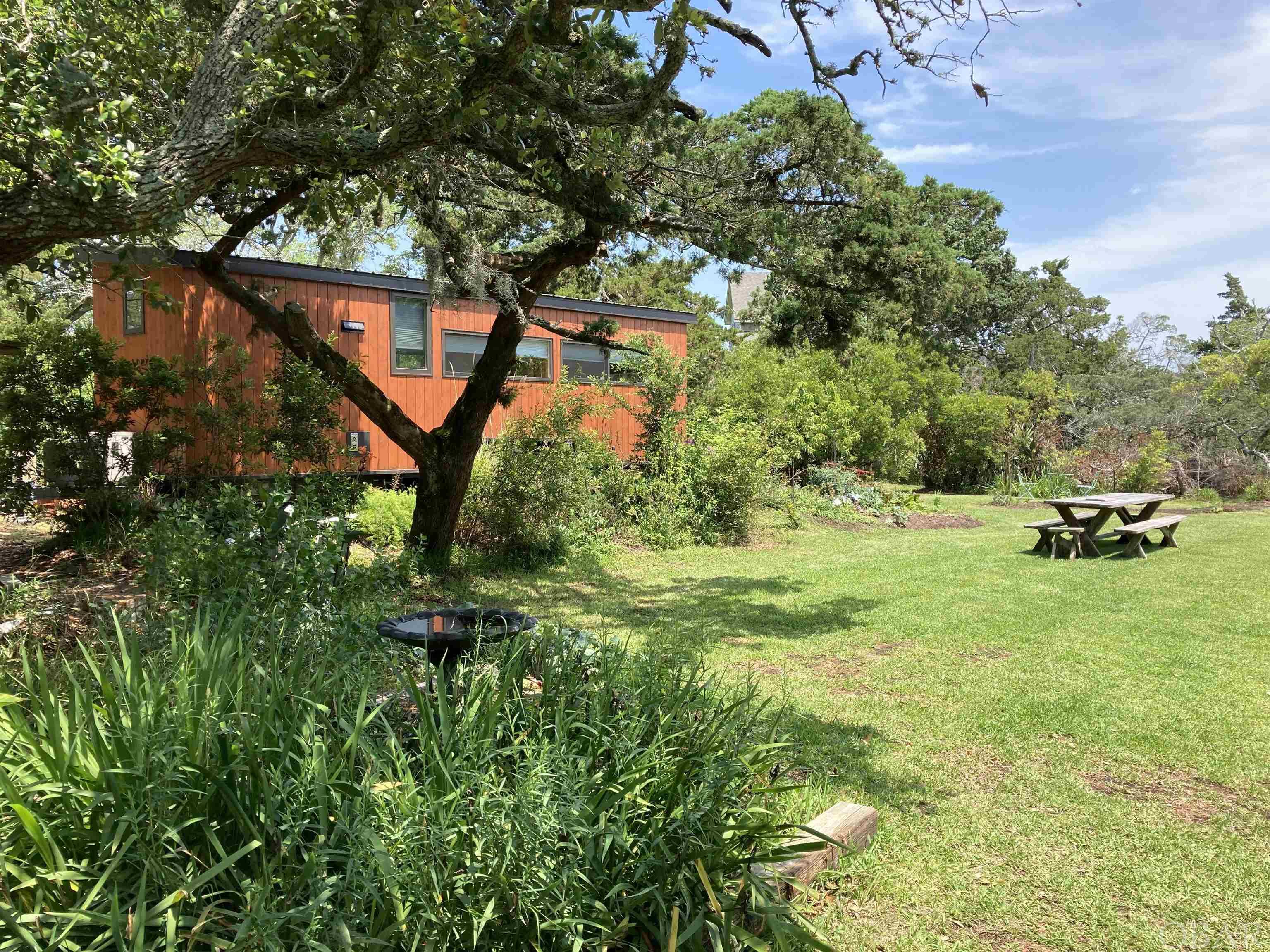 This property offers an incredible opportunity in a buildable lot with an existing tiny home. Boasting over 7,400 sq ft, find yourself tucked away in the enchanting gardens and sprawling green space. Centrally located within walking distance of Ocracoke's world class dining options. A 3 bedroom septic system on site. Approved for a 3 bedroom house. Site plan and septic permit in supporting documents.   A Boho XL 2020 tiny house by "Escape" conveys with the lot and provides ample rental revenue. Current owners operate as an AirBnb under "Island Tiny House."  Gas range, on demand hot water heater, Fujitsu mini-split, pine interior, and sliding barn door.   https://www.airbnb.com/rooms/46769108?source_impression_id=p3_1653760503_RJU5sABnYMTG27UG