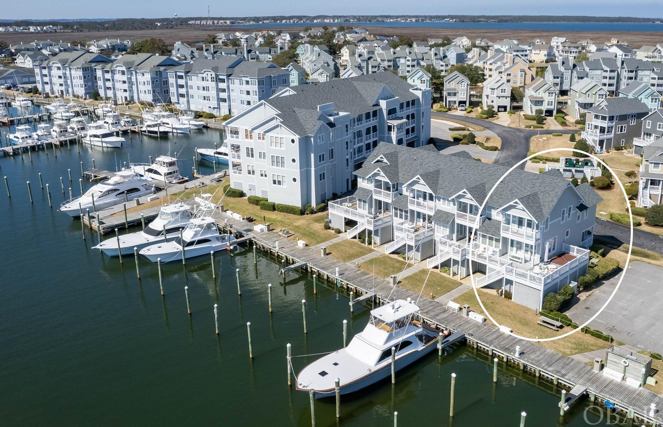 Stunning waterfront TOWNHOME with views of the Roanoke Sound and Pirate's Cove Marina. This end unit townhome is one of the most sought-after locations in Pirate's Cove with steps off the deck down to the dock.   Designed with an open floorplan, this 4BR, 3BA unit offers floor-to-ceiling windows, a spacious living/dining room and a kitchen perfect for entertaining or just relaxing while watching the boats return from their day of Off-Shore Fishing. The roomy kitchen features STAINLESS appliances, an eat on bar,  granite countertops and under-counter lighting. Sold FURNISHED, additional interior features include cathedral ceilings, master bedroom with ensuite bath and private balcony, three guest rooms, laundry room, gas fireplace, and a huge deck with HOT TUB.  Exterior features include multiple storage closets with additional enclosed space under the deck, an outdoor shower, dry entry, and a privacy wall.    Located in the Gulfstream subdivision of Pirate's Cove, community amenities  include: outdoor tennis, two pools, clubhouse, fitness center, playground, miles of perimeter docks, and sound access.  Located only steps to BlueWater Raw Bar and Grill, this unit offers location value and close proximity to marina activities. Staging by Site to Sea.