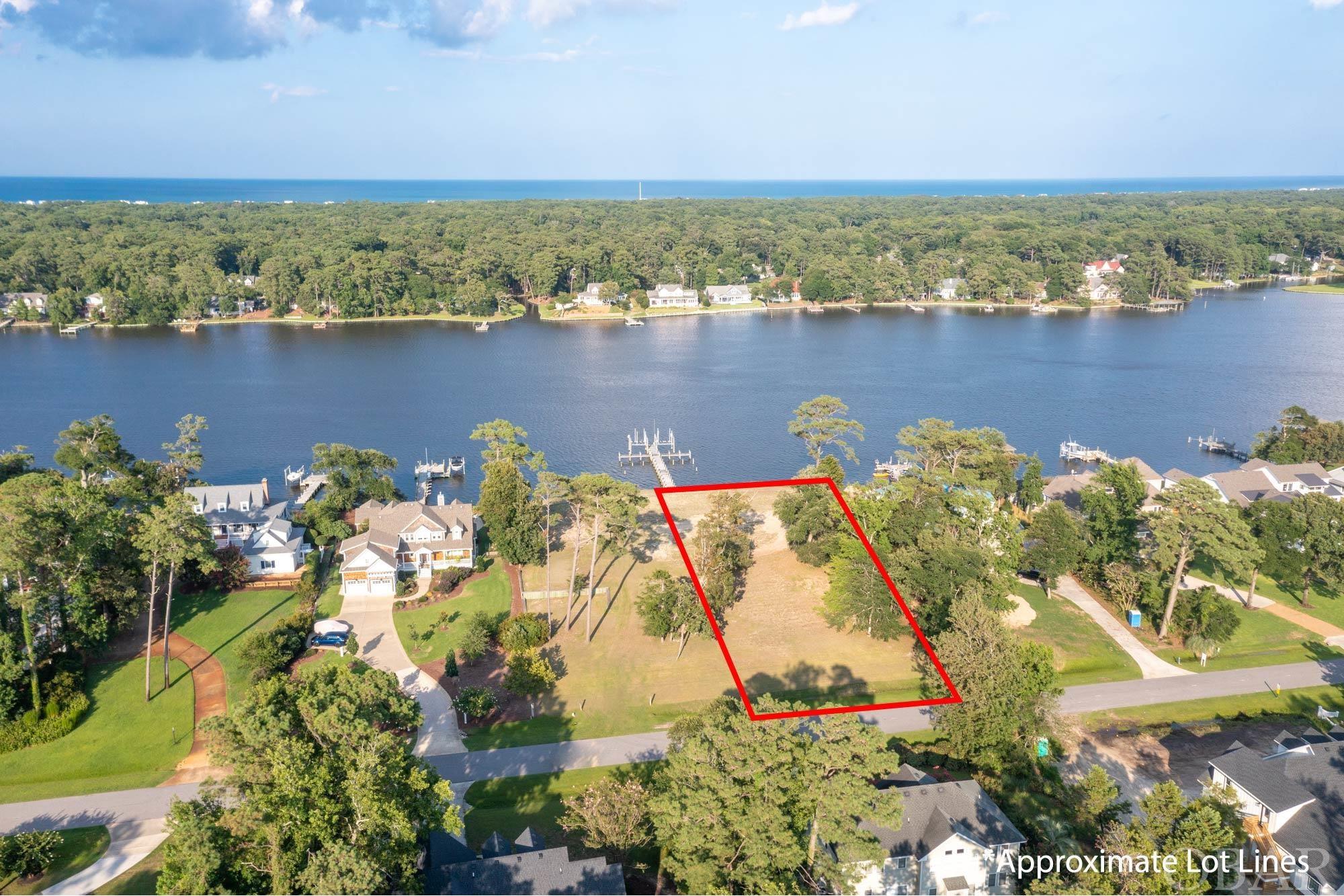 Located in the esteemed guard-gated community of Martins Point on the Outer Banks, this build-ready parcel with appx. 100 feet of water frontage sets the stage for the home of your dreams. Offering breathtaking vistas that stretch across the Jean Guite Creek, this approximately 30,000 square foot lot is one of the last available vacant lands in this peninsula community.  To top it off, it holds a 6’ wide by 125’ long Ipe Pier that includes 2 large boat lifts, mooring pilings, two 25’ finger piers, water service, and electric service.  The heavy duty, double reinforced vinyl bulkhead has been constructed with the best craftsmanship and materials available.  The ground elevation is estimated to be 10’, and the property is cleared and maintained.  Residents of Martins Point can take advantage of the superb amenities including a marina, boat ramp and dock, park, and 24-hour guard security.  Presenting an unrivaled lifestyle and location near the miles of Outer Banks beaches, this offering is not one to be missed. The adjoining lot is also available – see MLS 119788.