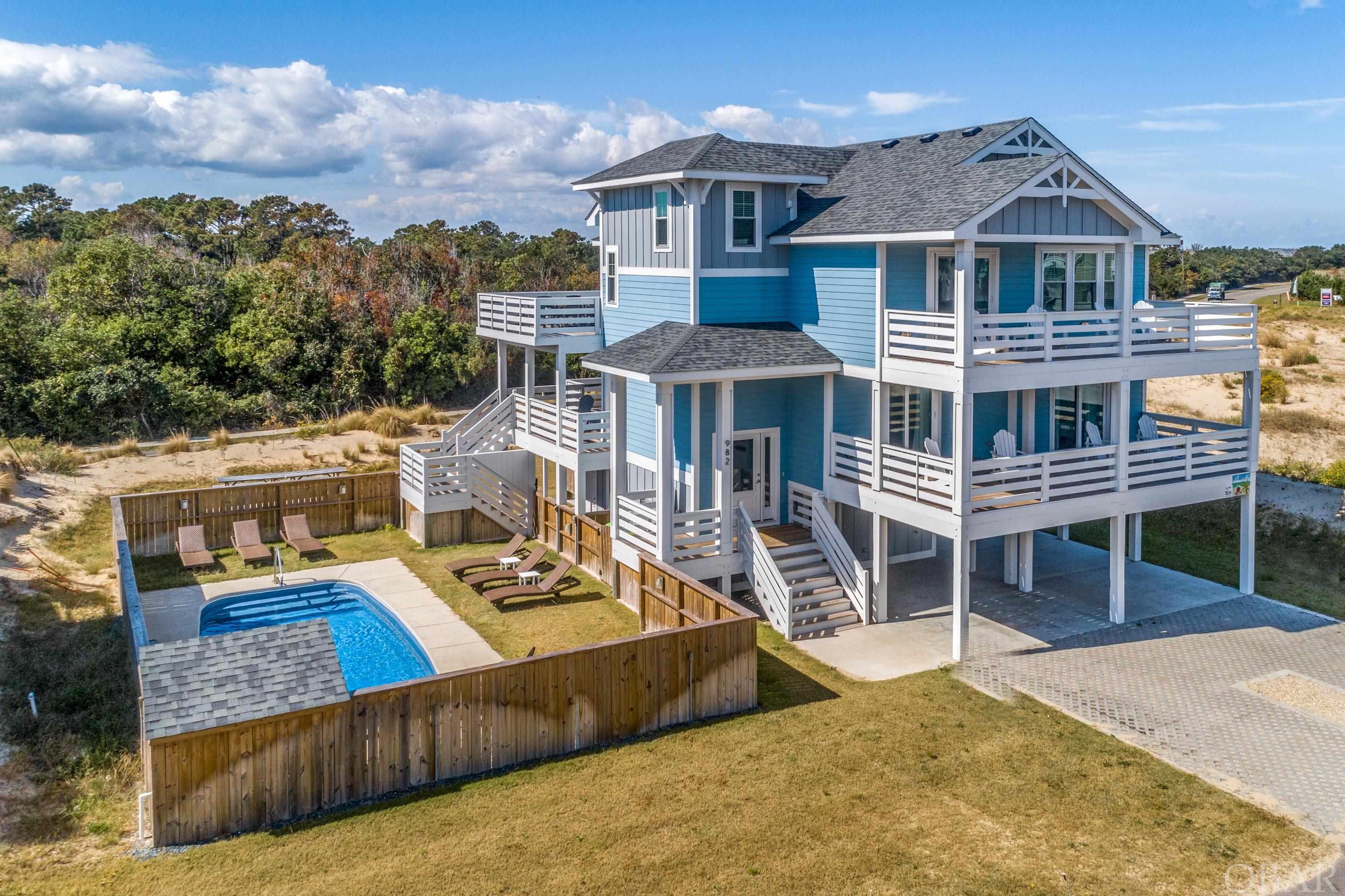 This handsome home was completed in November 2020 - Elevator, granite, wood floors, private pool! And it is an easy walk to the beach in Whalehead with the Perch walkway about 75' from the house.  The open concept living includes the living, dining and kitchen for ultimate family gatherings. You will love the huge kitchen with beautiful granite countertops, soft close, white-painted cabinets and stainless steel appliances. The large east deck off living area is partially covered for protection and gives a glimpse of the ocean.  There is the primary bedroom with ensuite bath with two sinks and custom tiled shower. Down the hall is a nice southwest deck for evening sunsets.  A work space was created in the loft. Grab the elevator and head down to the mid level which has 2 bedrooms with ensuite baths along with another bath and 2 more bedrooms. All 4 of these bedrooms have direct deck access. The ground level has a rec room with kitchenette that gives access to the private pool and back yard.  Rents in 2022 were limited to 10 summer weeks & owner saw income of $69,054! Laminate wood flooring throughout except baths are LVP, tiled showers, rec room has mini split for maximum efficiency, LP Smart Siding, and is about 500 yards to beach.  Located on the oceanside of Monteray Shores, this home gives you the best of both worlds! This street happens to have a number of year round residents.  Enjoy community amenities at the Clubhouse with large pool, tennis courts a playground and boat ramp and a great community for walking and bike rides.  Close to restaurants and shops and the historic Corolla community with Lighthouse and Whalehead Club.