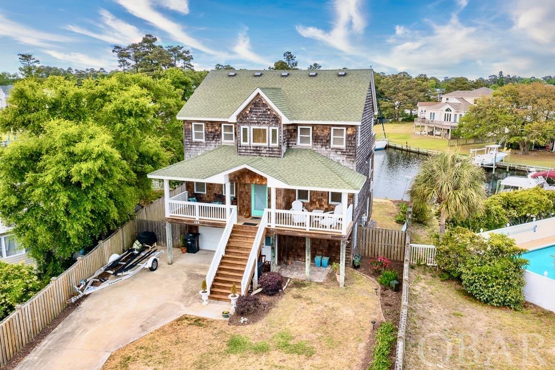 Water Views Galore!  Park your boat on your own private boat lift, fish and/or go crabbing from your boat dock and kayak or SUP right off of your back yard all while enjoying the beautiful wildlife of the OBX.  Well maintained and upgraded Canalfront home with expanded water views and numerous custom features.  This home is Special in many ways including Beautiful Water Views from two of the bedrooms and the two large decks facing the water.  Enjoy extra wide canals that go in three different directions for expanded water views.  Located on a quiet cul-de-sac in the gated community of Colington Harbour, this waterfront home has it's own private dock and boat lift.  On the ground floor is a Home Theater room with large screen TV, recliners, a pool table, and a "like new" pullout queen sized sleeper sofa for extra sleeping arrangements. The three bedrooms are located on the mid-level along with decks on both the front and rear of the home. Upstairs you will find a generous sized great room with vaulted ceilings, a gas fireplace, custom solid wood craftsman style paneling, a powder room and a gourmet kitchen that includes quartz countertops, double refrigerators & stainless appliances. Outside, you will find the boat dock and boat lift, a landscaped and fenced-in yard, and an outside shower plus room to add a pool. The primary bathroom has been completely remodeled with custom cabinets & drawers as well as an extra custom large tiled shower with double shower heads. The primary room closets have also been custom built to maximize spacing & storage. This home was quality built by Matt Tappero of Coastal Construction of NC and is "High & Dry".  Located in an "X" Flood Zone (meaning that NO Flood Insurance is required), this home has NEVER Flooded including during Hurricane Irene (2011) when may other nearby homes did experience some flooding.  Colington Harbour HOA fee is only around $320 per year and includes a 24 hour security guard at the gate, a private beach, playground, picnic area, boat ramp and more.  You can join the swimming pool membership for around $200 per year.  One of the owners/sellers is a licensed real estate broker in NC.