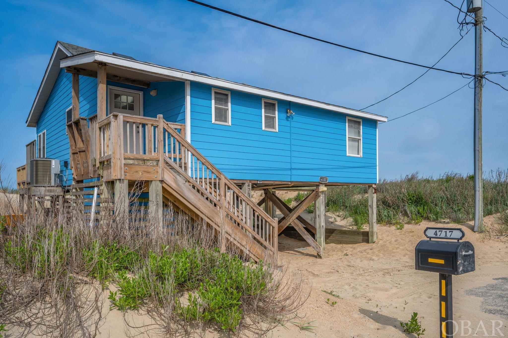 This oceanfront property is a three-bedroom, two-bathroom home offering a tranquil and idyllic setting and stunning ocean views. The property was completely remodeled in 2004, including new roof, pilings and siding on the outside, as well as everything on the inside. This is a solidly built oceanfront home that was originally a second home and has never been a rental. This beach getaway is ideal as a second home or income producing property. (Rental projection in Associated Documents estimates upward of $108,000 advertised rental income.) Upon entering, you are greeted with a wide open floor plan with two large skylights inviting natural light to flood the space, and a large picture window which provides breathtaking views of the ocean. The light-toned hardwood floors run throughout the house.  There is also a half-glass door, with internal mini blinds, leading out to the oceanfront deck.  Stepping outside, the home reveals its true gem—an expansive oceanfront laid out before you. The crashing waves and salty breezes provide a constant reminder of the home's unparalleled location. The spacious outdoor deck offers a wonderful spot to sunbathe, entertain, watch a stunning sunrise over the ocean, or dine al fresco. The outdoor shower is adjacent. The kitchen area offers wood cabinetry in a honey tone, a granite counter, dishwasher, newer fridge, and a stove/oven with microwave. The cottage has three bedrooms. The oceanfront room boasts large windows that showcase stunning ocean vistas, providing a serene backdrop for relaxation. The other bedrooms are on the south and west side of the layout. The home has two full bathrooms each with glass door showers, commodes, and vanities.  One bathroom can be shut off from the main living area to create private accommodations. This is a charming coastal retreat with spectacular ocean views and a desirable location. Close to the Kitty Hawk Pier, many local restaurants, retail stores, and grocery shopping, this prime location proves to be one of the most convenient spots in Kitty Hawk. The property is being sold As Advertised.